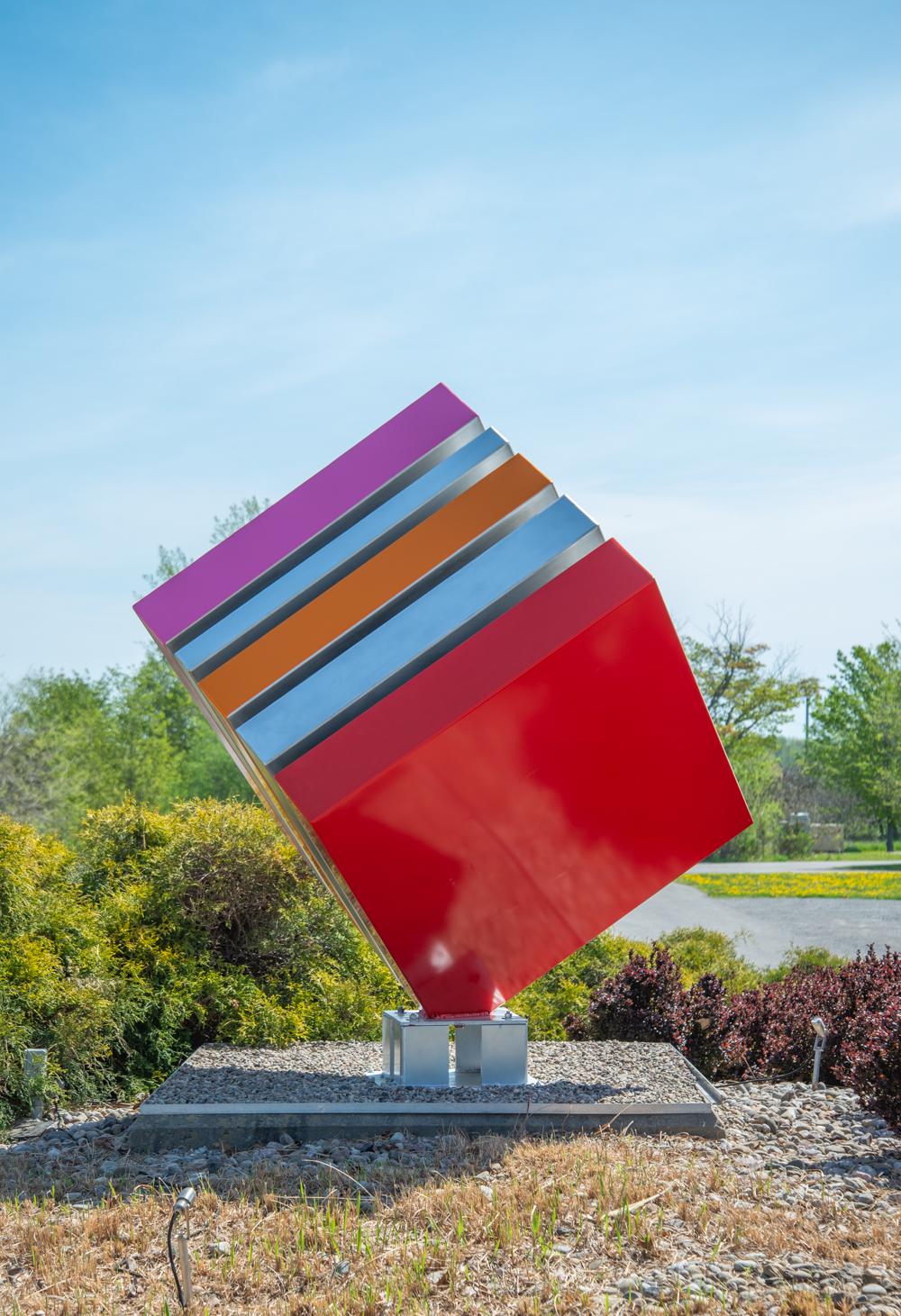 La dernière sculpture de Philippe Steele - un grand cube d'acier aux couleurs de bonbons - est composée de bandes peintes en rouge, orange et rose vifs qui s'équilibrent sur un coin. L'artiste québécois conçoit des pièces de pop art qui reflètent la