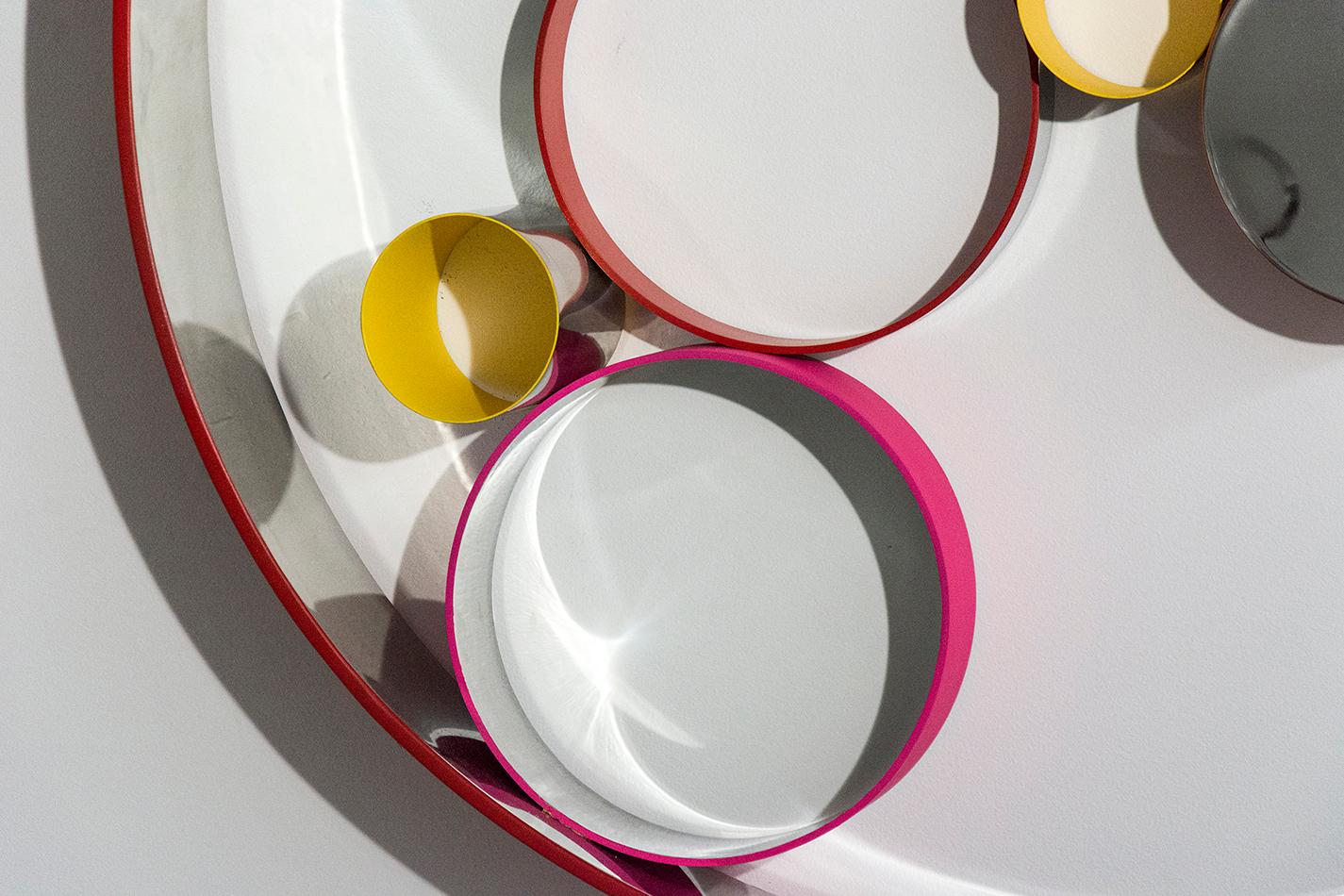 A playful collection of steel rings and disks bubble and swirl within a polished hoop, gleaming on the inside and matte poppy red on the outside. The elements of this modernist inspired wall tondo by Philippe Pallafray are polished to a high sheen