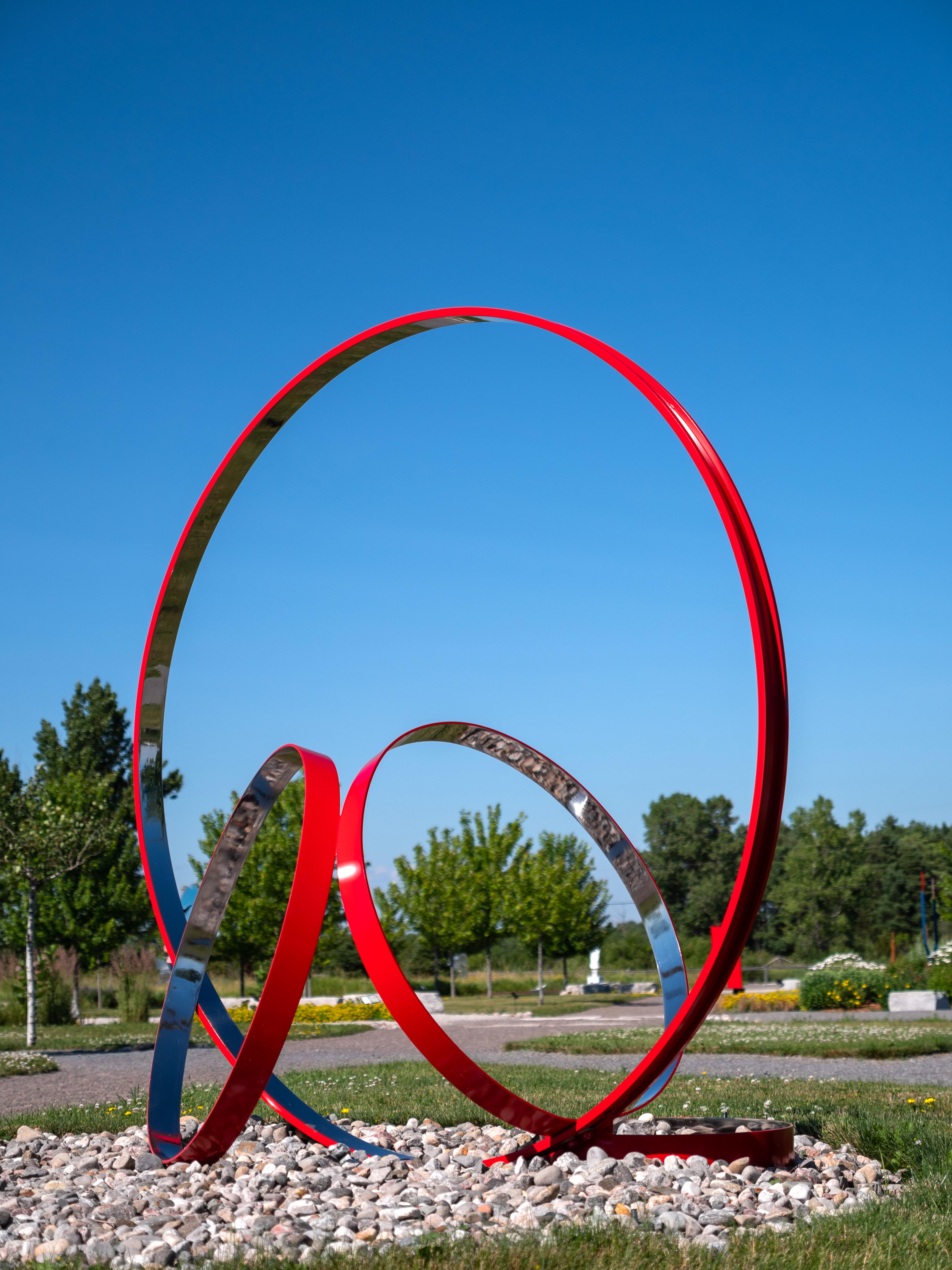 Four stainless steel rings, one side in poppy red, are curated into a elegant outdoor composition by Philippe Pallafray. This minimalist sculpture plays with space framing the landscape yet sitting in contrast with it. The title of the sculpture may