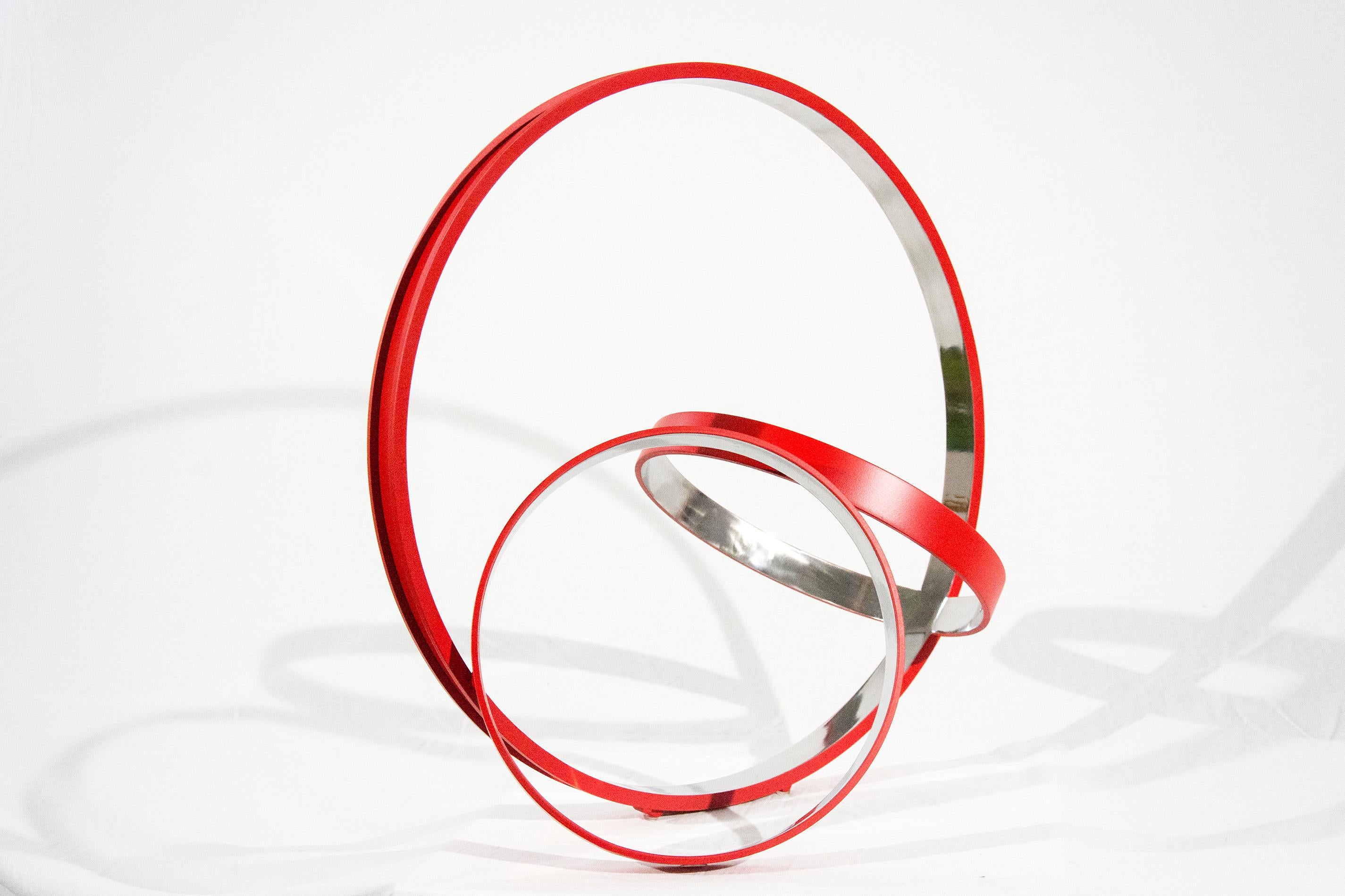 Trois anneaux en acier inoxydable, polis à l'intérieur et d'un rouge cardinal mat à l'extérieur, sont réunis dans une composition élégante et minimaliste par Philippe Pallafray. Le titre de la sculpture peut se traduire par 
