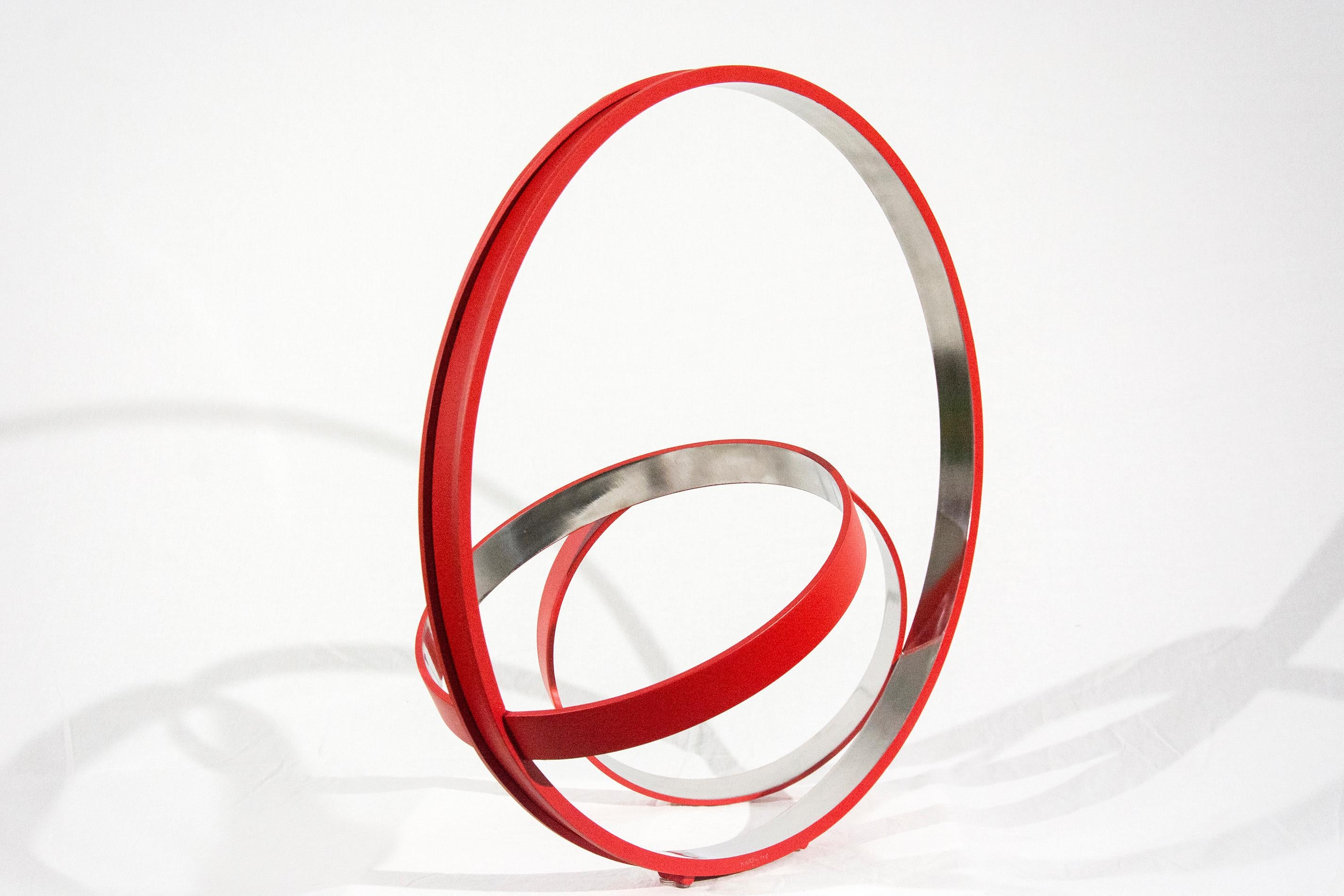 Three stainless steel rings, polished on the inside and a matte cardinal red on the exterior, are curated into an elegant, minimalist composition by Philippe Pallafray. The title of the sculpture may translate as ‘no time’ or timeless suggesting
