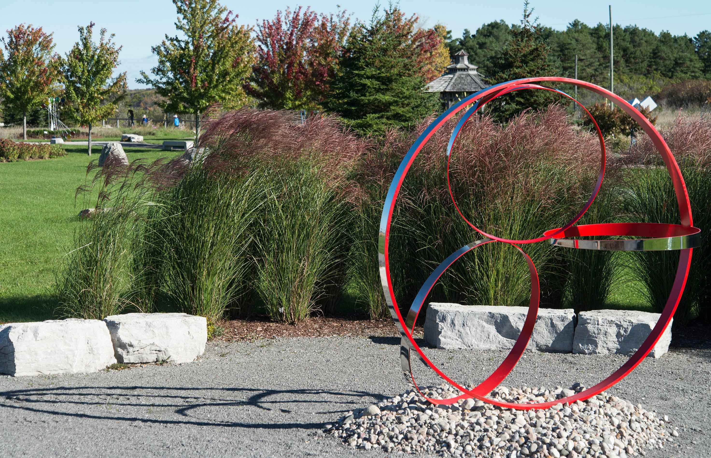 Four stainless steel rings, one side in poppy red, are curated into a elegant outdoor composition by Philippe Pallafray. This minimalist sculpture plays with space framing the landscape yet sitting in contrast with it. The title of the sculpture may