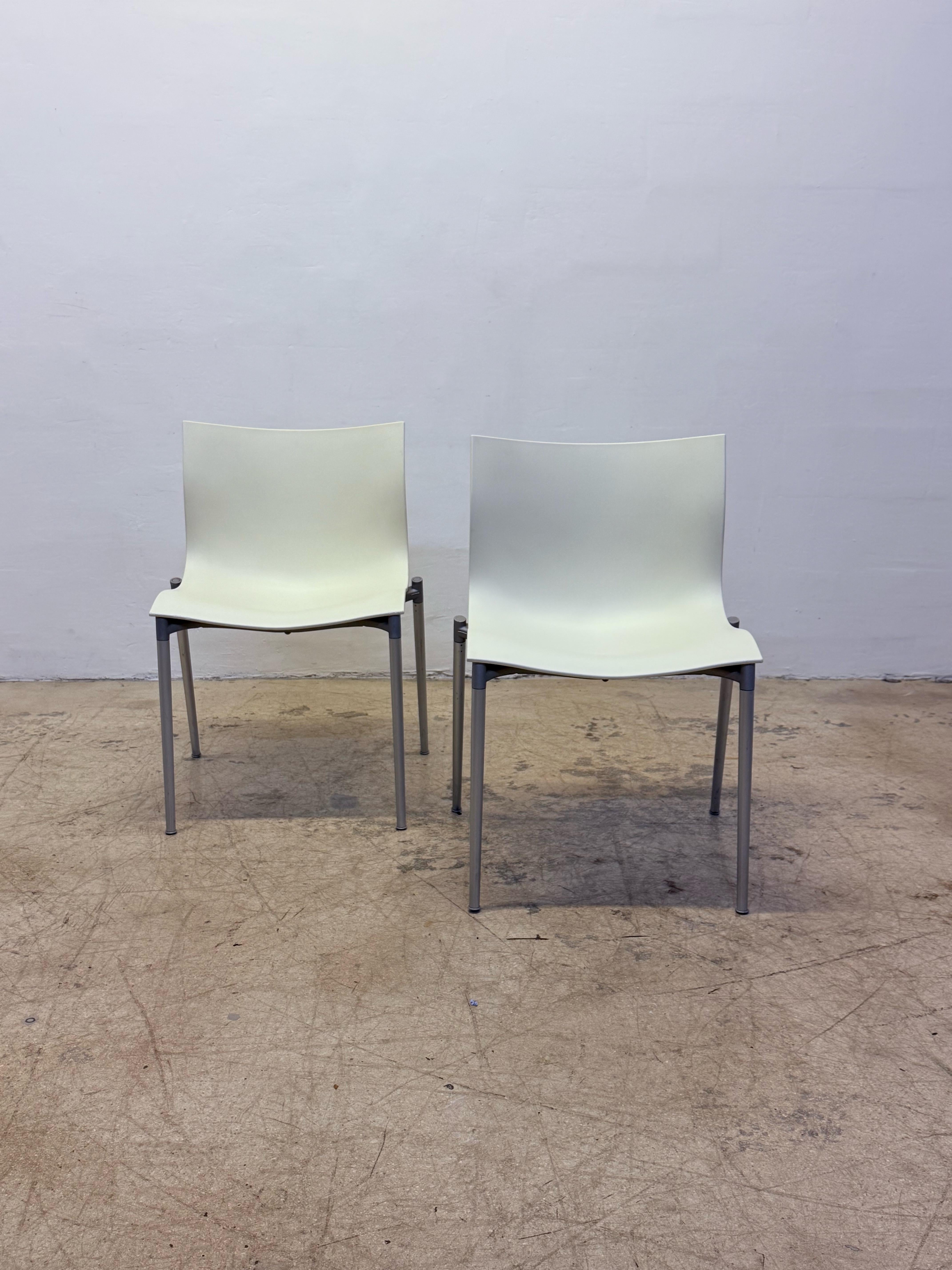 Pareja de sillas apilables Cam El Eon con asientos curvos de plástico color crema sobre armazones de aluminio gris metalizado, diseñadas por Philippe Starck para Dríade Aleph, Italia.