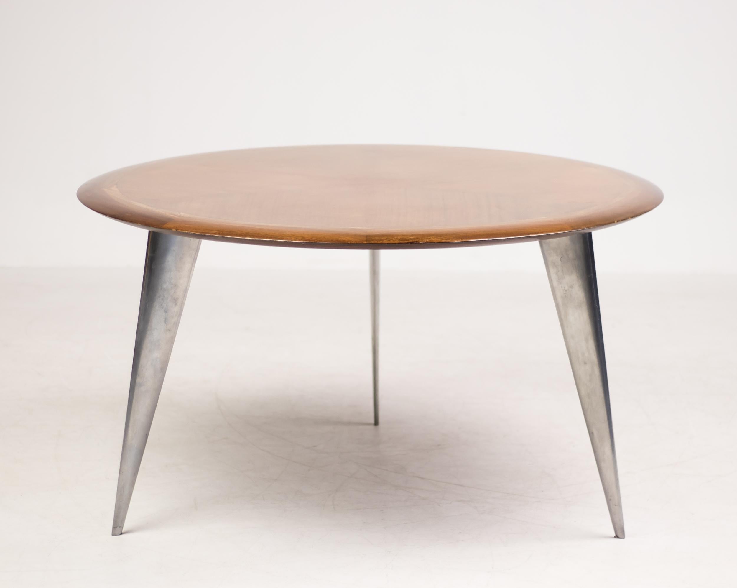 Round dining table in mahogany designed by Philippe Starck in 1987 for Aleph France; a division of Driade.
A flying saucer-like sleek bookmatched mahogany veneer top dining table over three sharply angled polished cast aluminium legs.
Each leg