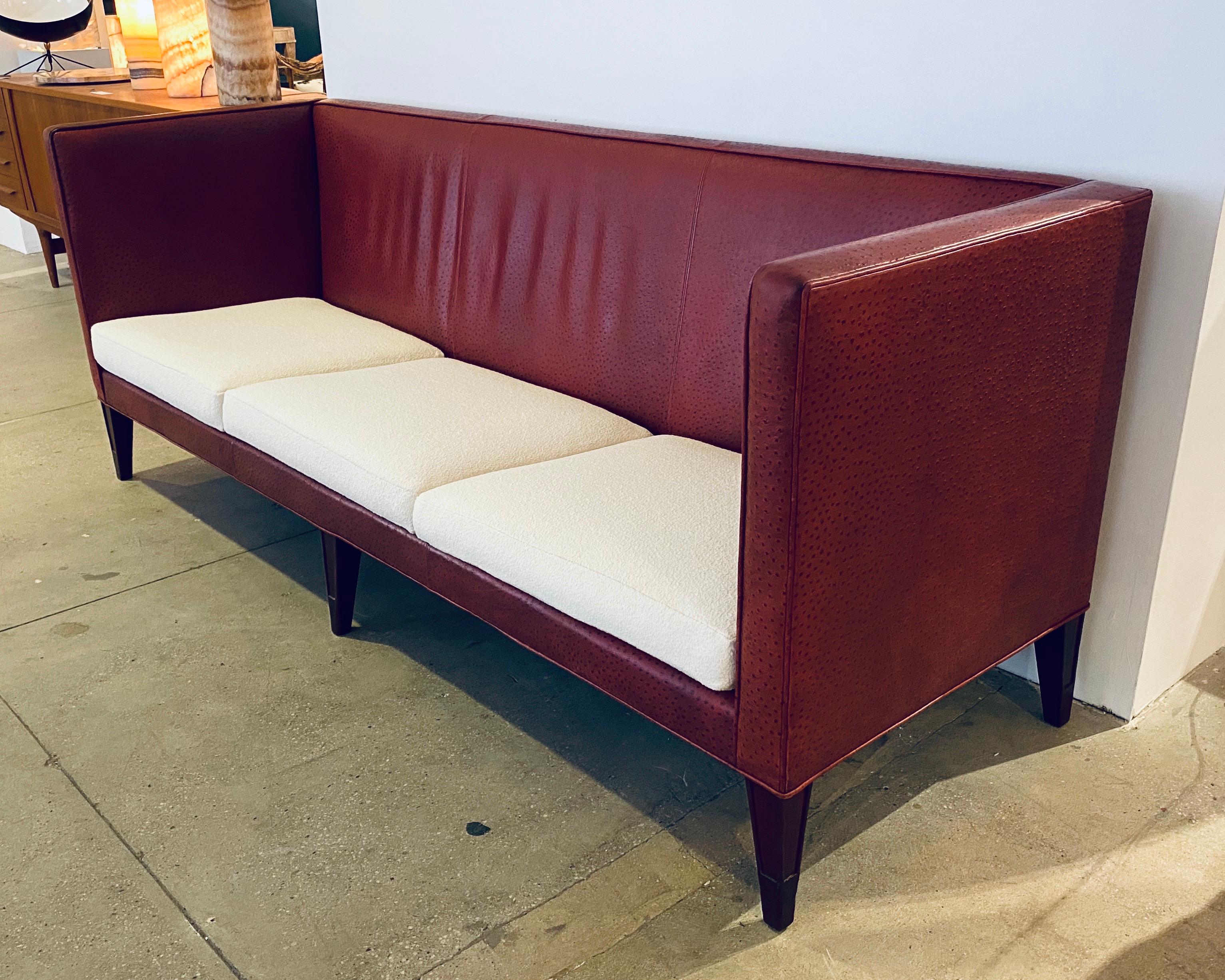 A dramatic custom long leather sofa designed by Philippe Starck for the famed redwood room of San Francisco Clift Hotel. The sofa has reddish ostrich embossed leather frame with newly upholstered Knoll bouclé cushions.