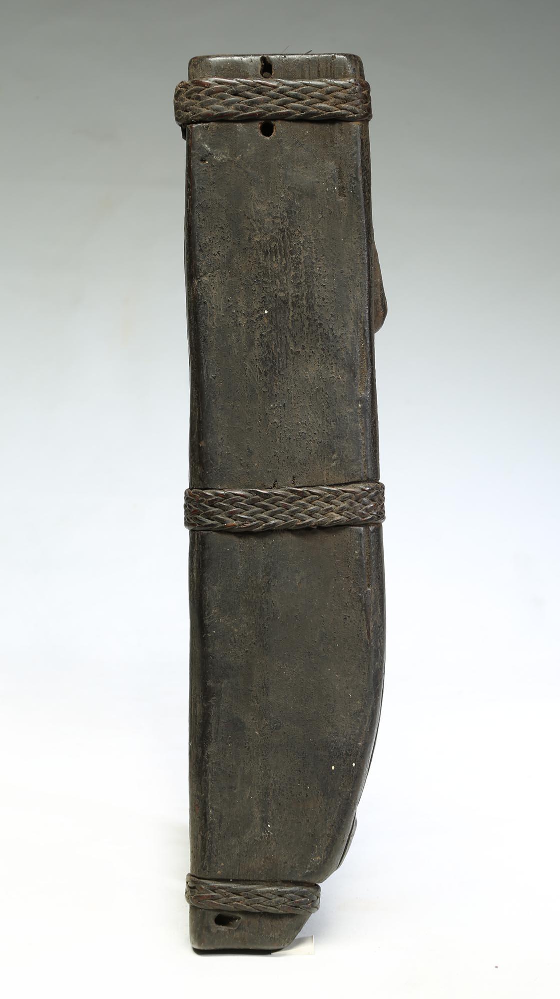 Carved wood knife or sword scabbard from the Philippines, with carved standing figure with open legs and hand up by sides of head. Woven raffia bands to hold the front and back parts of the scabbard together. 
Wonderful encrusted surface. Measure: