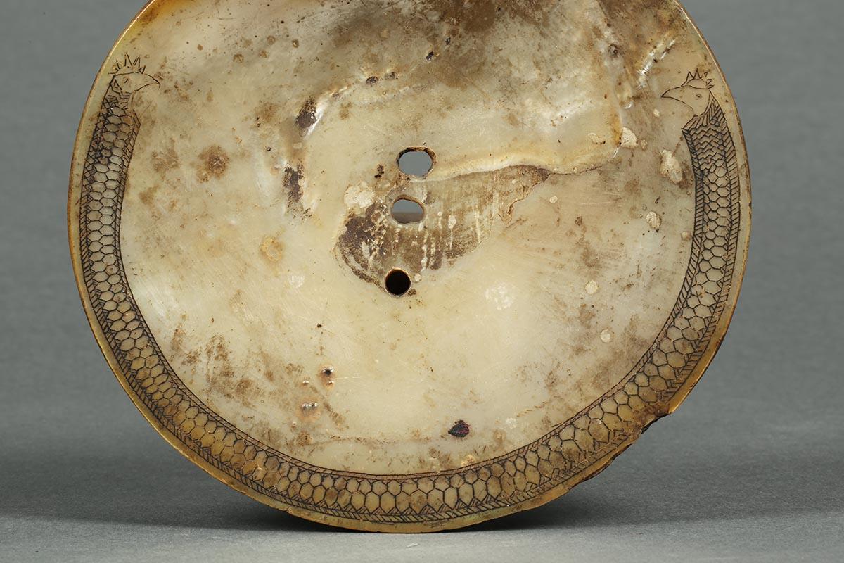 An early 20th century shell waist band ornament from the Philippines with refined incised black design ending in two bird heads. Old with signs of age, wear and yellowing. Measures: 5 3/4