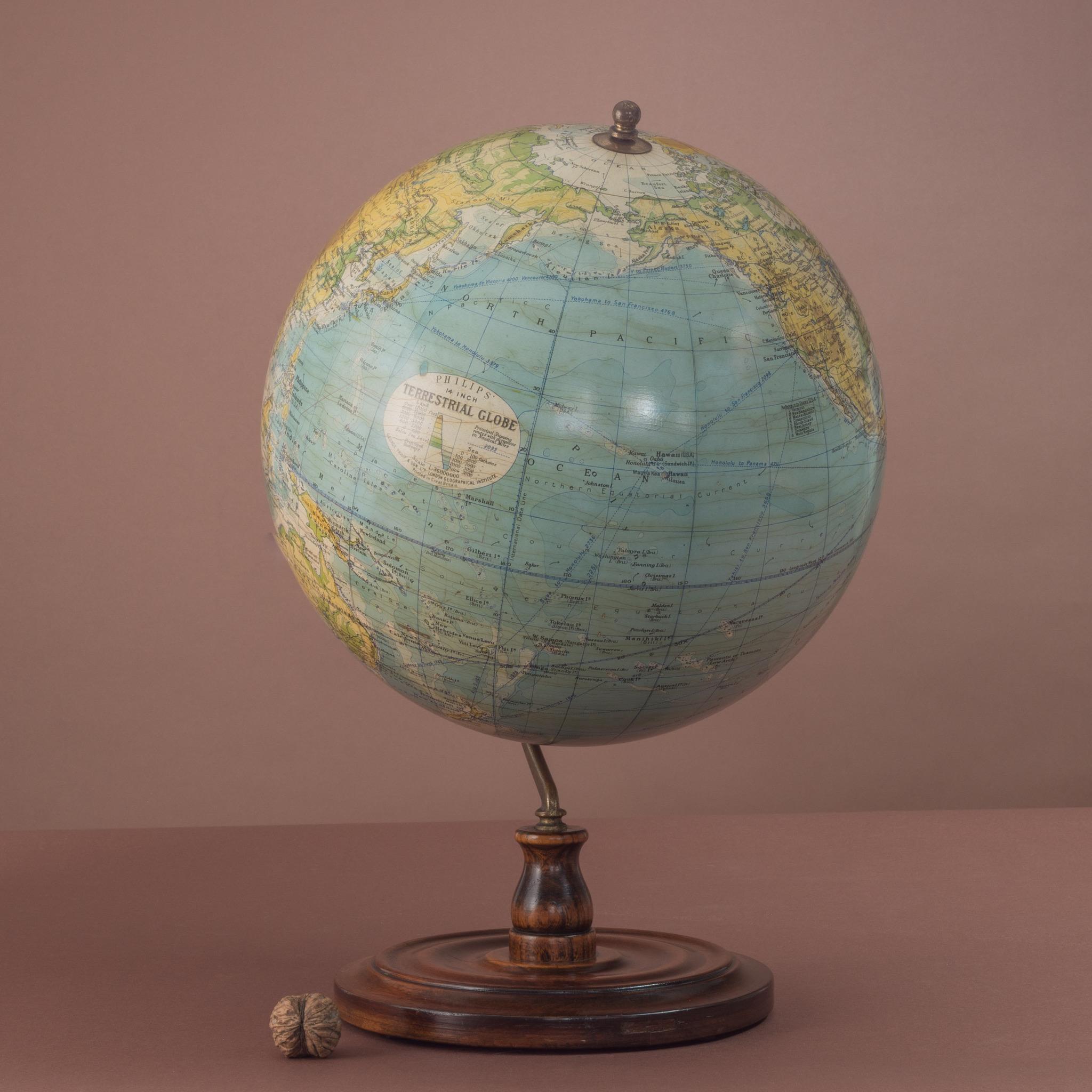 A substantial 14 inch gesso terrestrial globe by Philips of London on brass inclined plain mount attached to original turned wooden based upright with axes secured at the top by a brass finial. Has Air Ministry stamp on the underside of the base.
