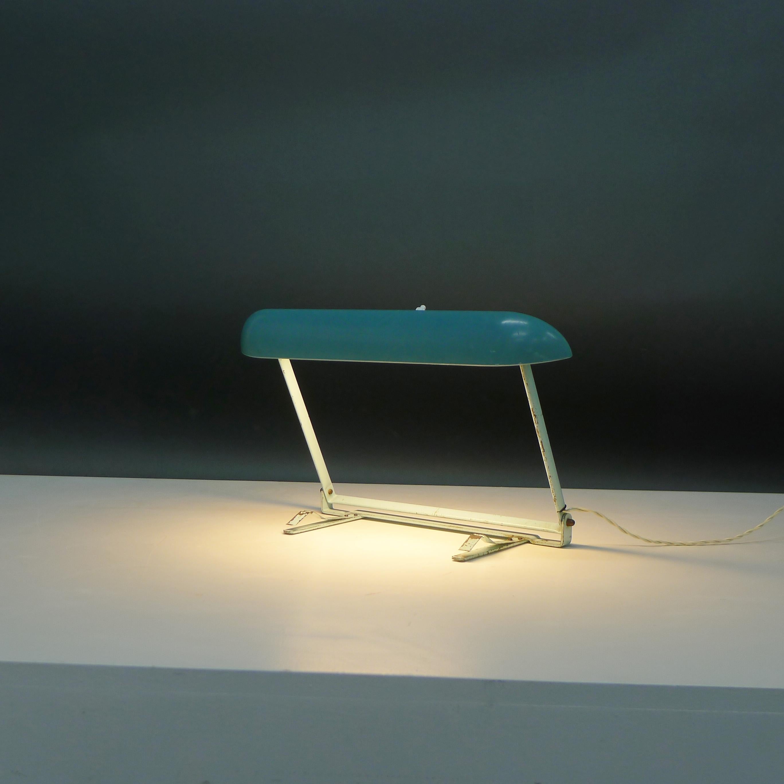 Eye-catching 1950s vintage desk light in a light turquoise colour, the design attributed to Charlotte Perriand for Philips. With curved bakelite shade over the neon strip bulb, on a lacquered metal hinged base, with clips to attach to your desk and