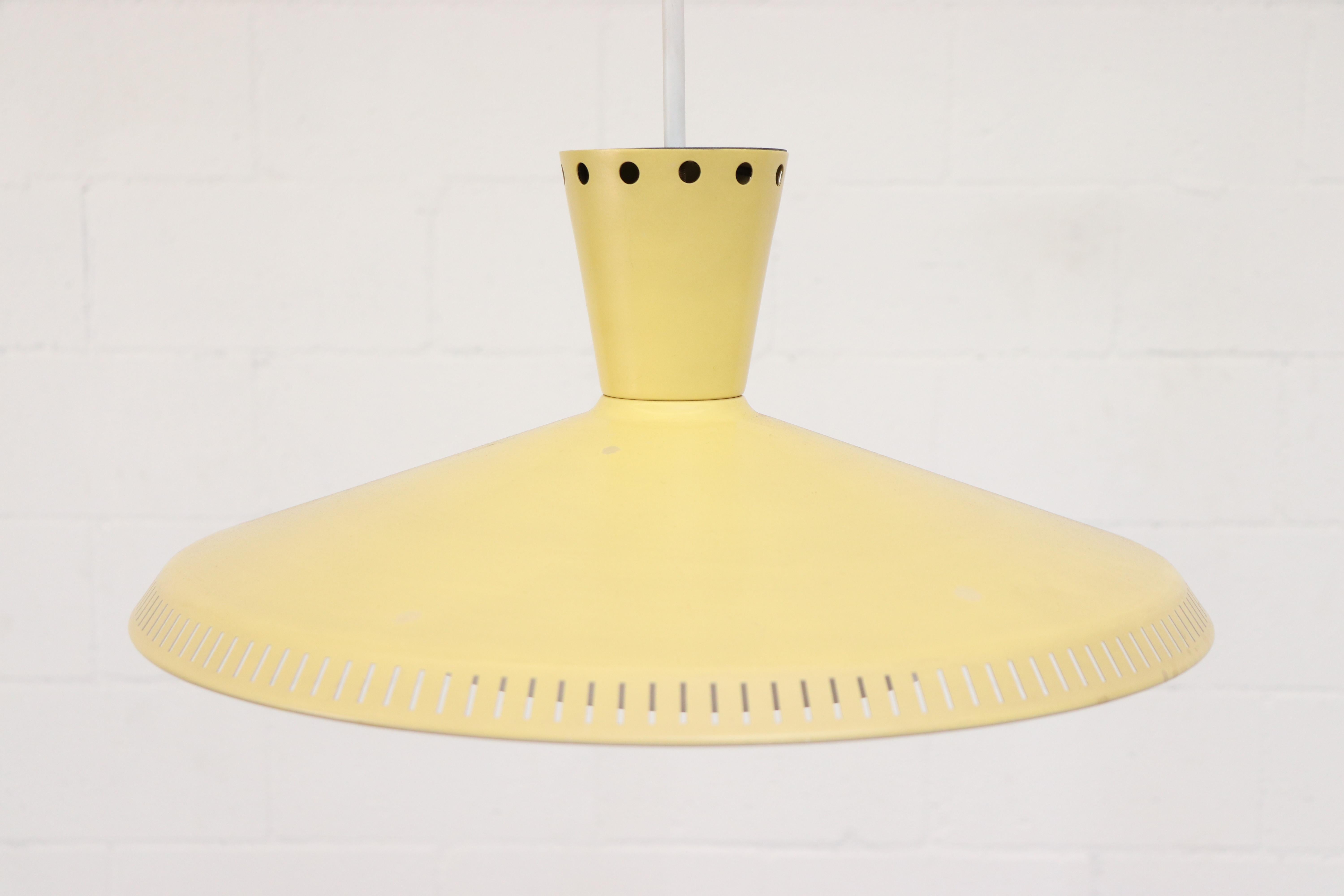 Philips ceiling pendant in pale yellow with Acrylic diffuser. Enameled metal and rectangular slat perforated bottom rim, circular perforated top rim. In original condition with some visible signs of wear consistent with age and use.