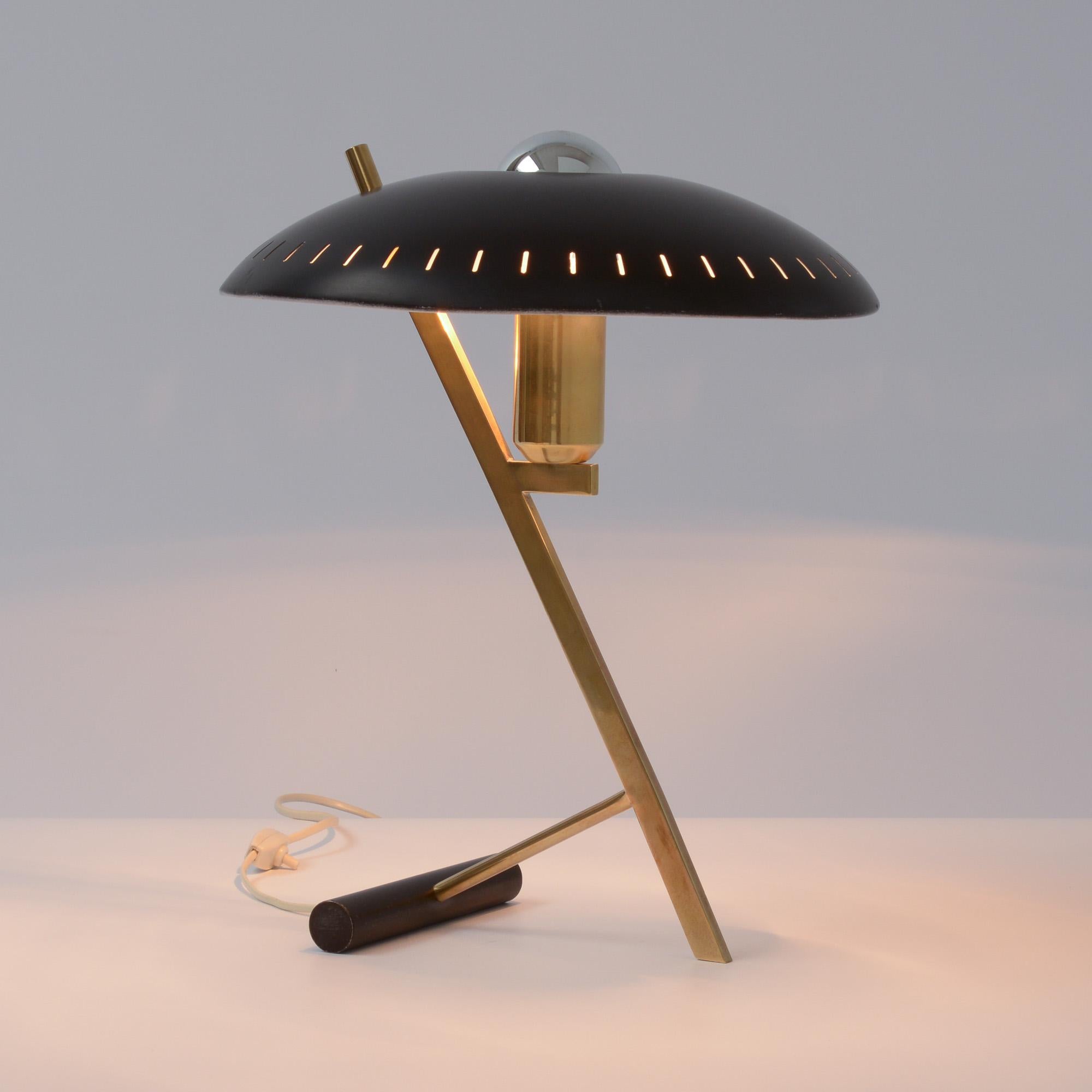 This beautiful desk lamp was designed by Louis Christiaan Kalff for Philips, Eindhoven in 1955.
It has a black curved perforated metal shade and a brass frame.
This lamp is an early production. It is in good vintage condition.
All our lamps are