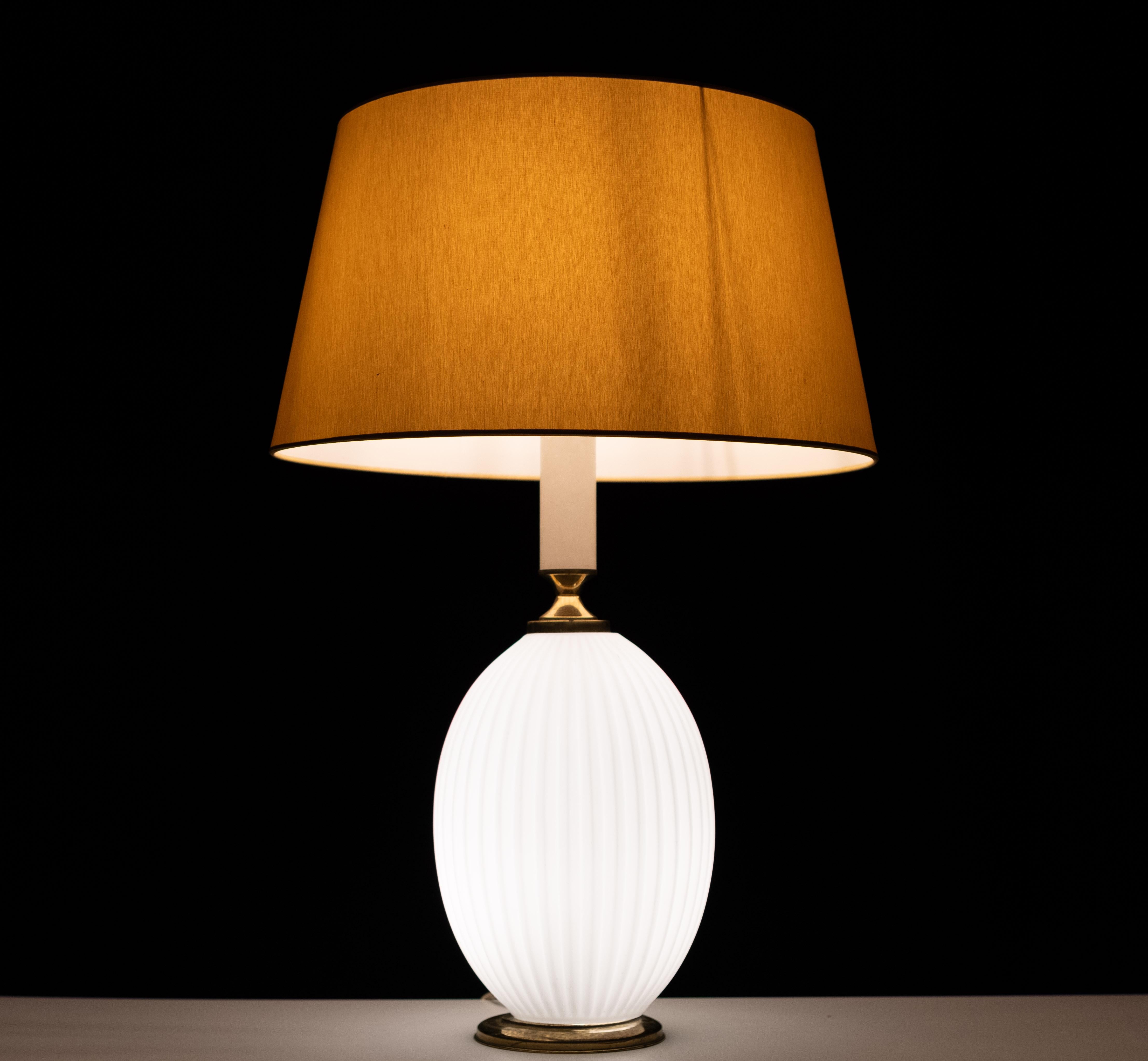 Sehr schöne stilvolle Tischlampe. Gerippter Sockel aus Milchglas, Füße aus Messing.
Inklusive Farbton . Zwei Glühbirnen, eine im Sockel und eine an der Spitze.
Louis Kalff-Entwurf aus den 1950er Jahren für Philips 