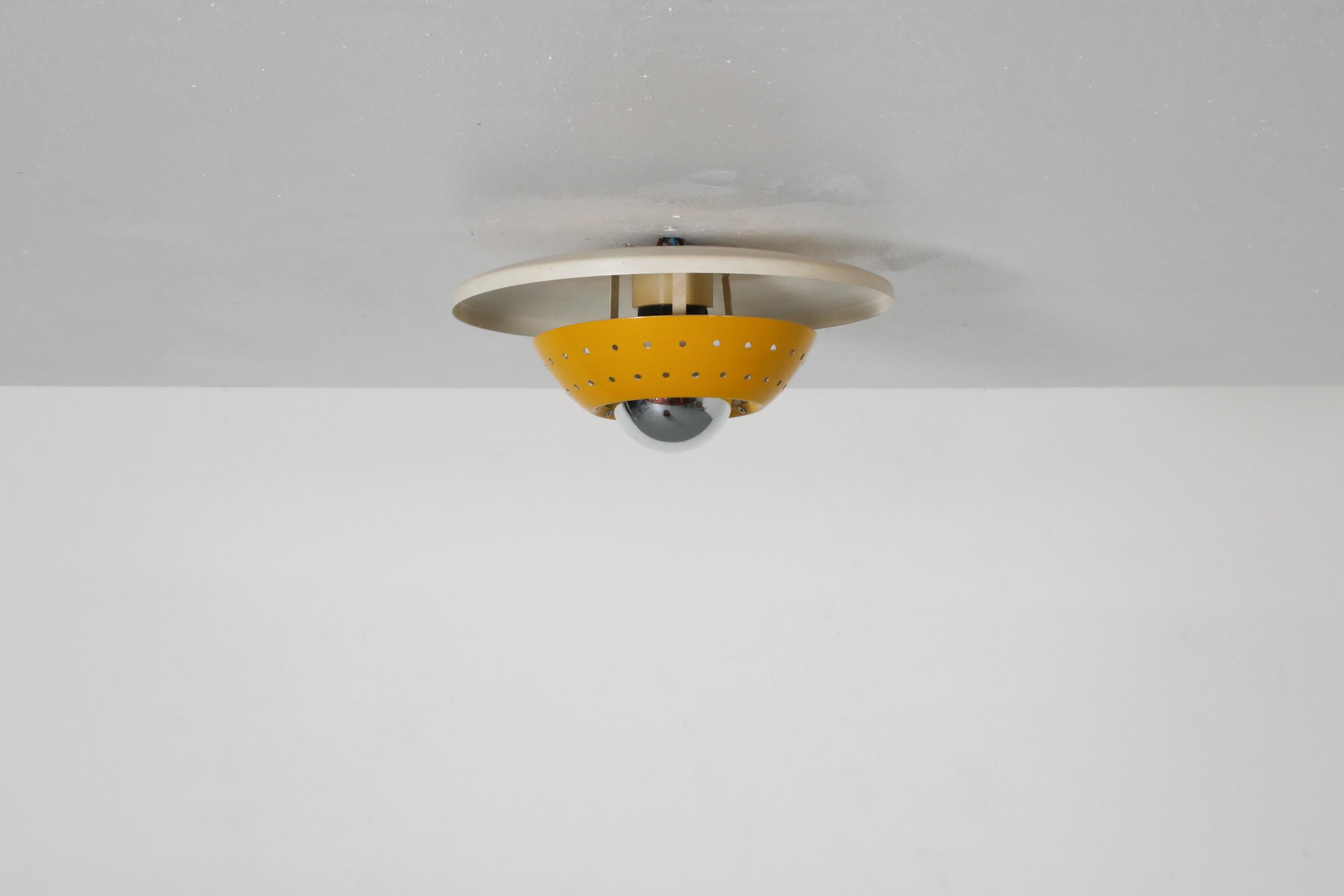 Dutch Mid-Century, UFO-styled ceiling lamp attributed to designer Louis Kalff for renowned electronics and lighting manufacturer Philips, Netherlands. Stylishly designed with a white enameled metal dome base and a contrasting yellow enameled