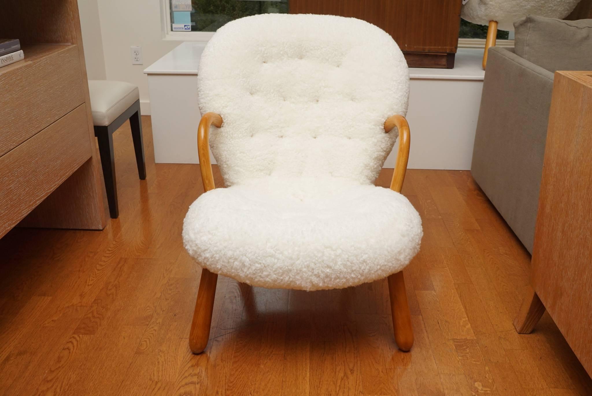 Rare! a pair of oak clam chairs, designed by Phillip Arctander of Denmark for Paustian. The chairs are upholstered in a luscious, irresistible sheepskin. 
Not only are they handsome, the chairs, 