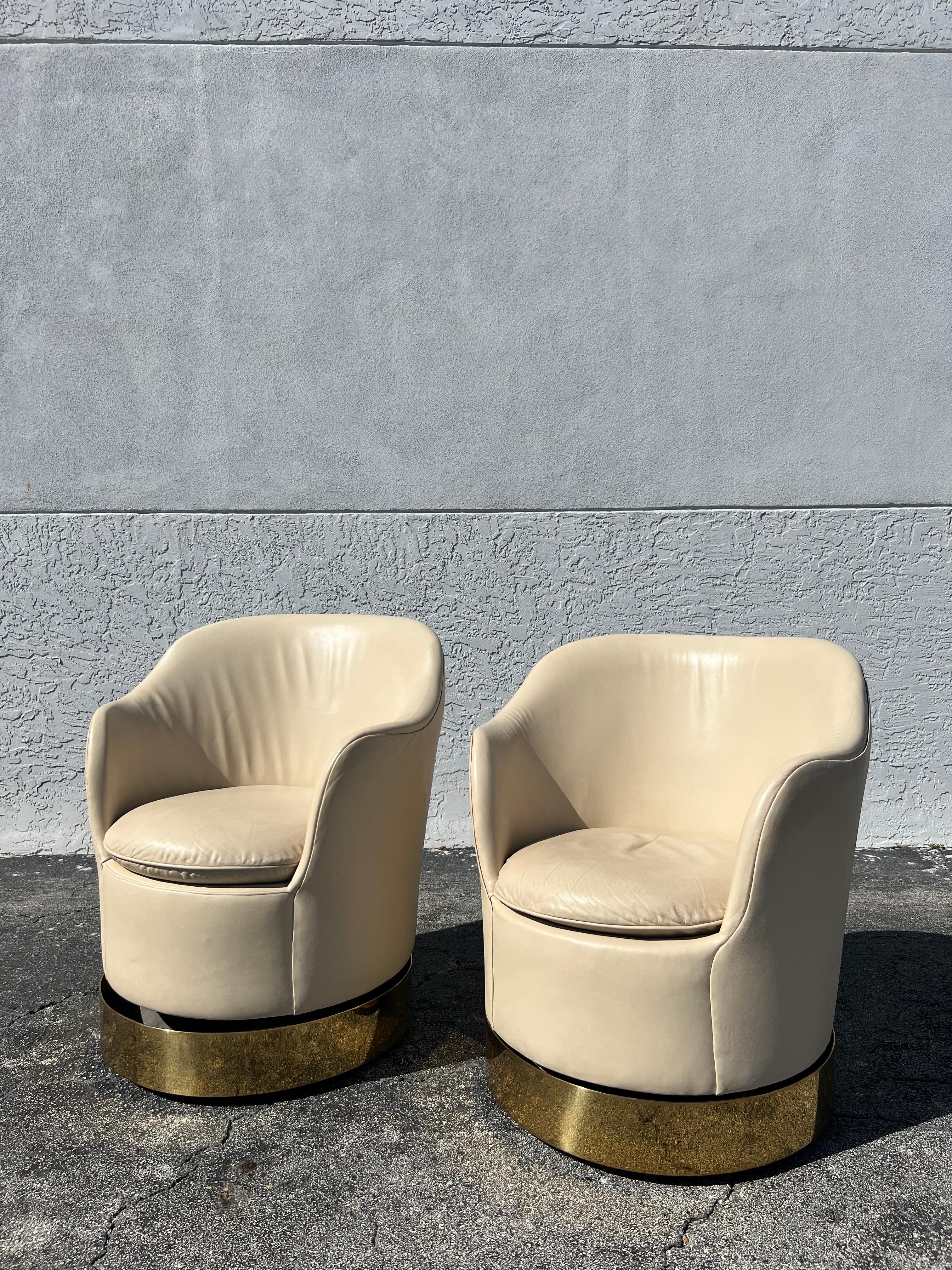 Pair of Phillip Enfield brass swivel lounge chairs. The chairs swivel and tilt, the bases are also on wheels. The chairs are adjustable in height, however the bases must be removed to perform this. We have not adjusted them, so the heights vary