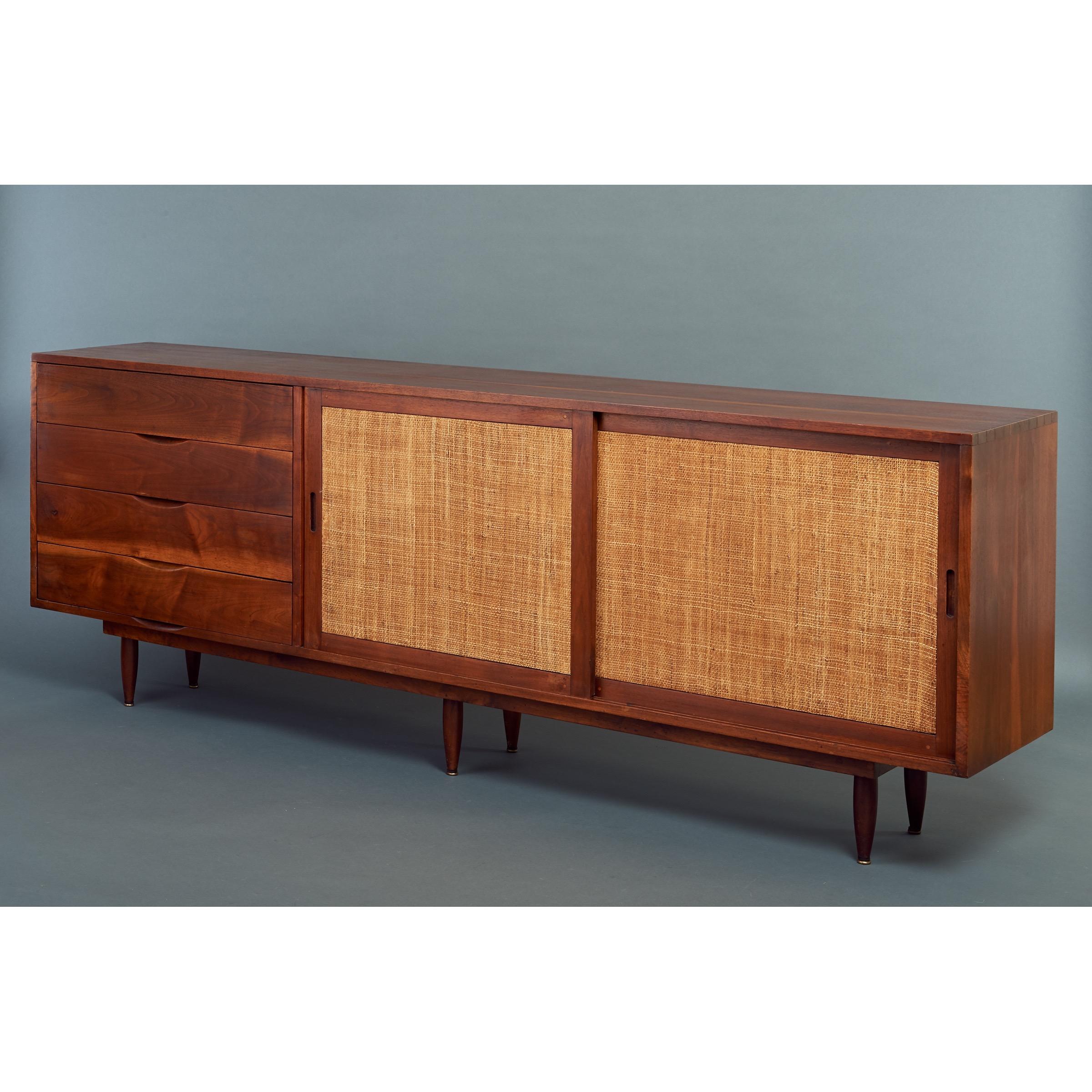 Phillip Lloyd Powell (1919 - 2008)

A rare and consequential seven-foot long credenza by Pennsylvania Studio Craft Movement master Phillip Lloyd Powell. With a substantial and lustrous walnut frame, two textural rattan sliding doors, four drawers
