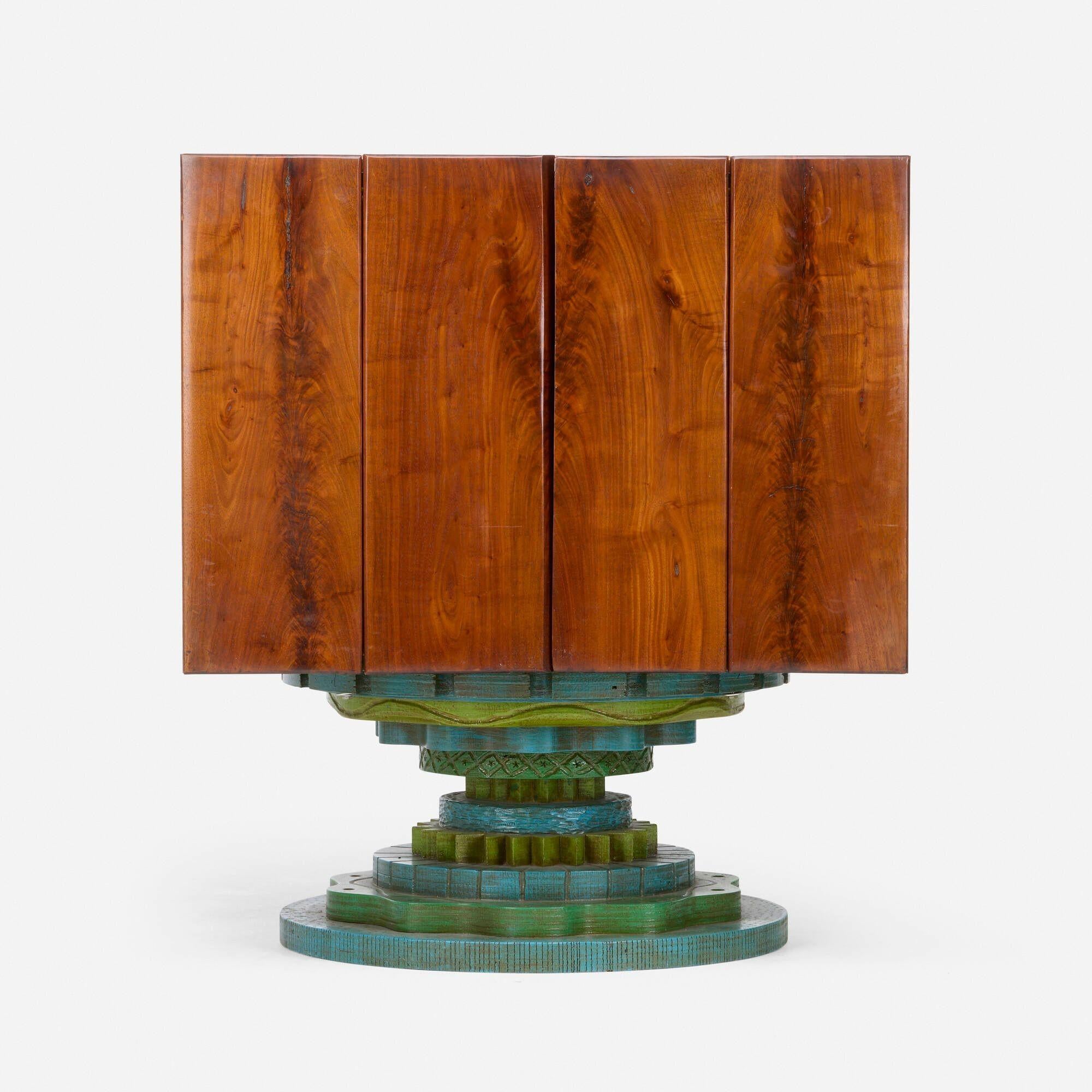 Phillip Lloyd Powell Rotating Walnut Case / Bar, 1965
Walnut, Carved and painted wood base, cane, felt interior
Dimensions:
39½ high
 35 wide
29¾ deep
A distinctive rotating case or bar by Phillip Lloyd Powell, crafted in 1965. The piece features a