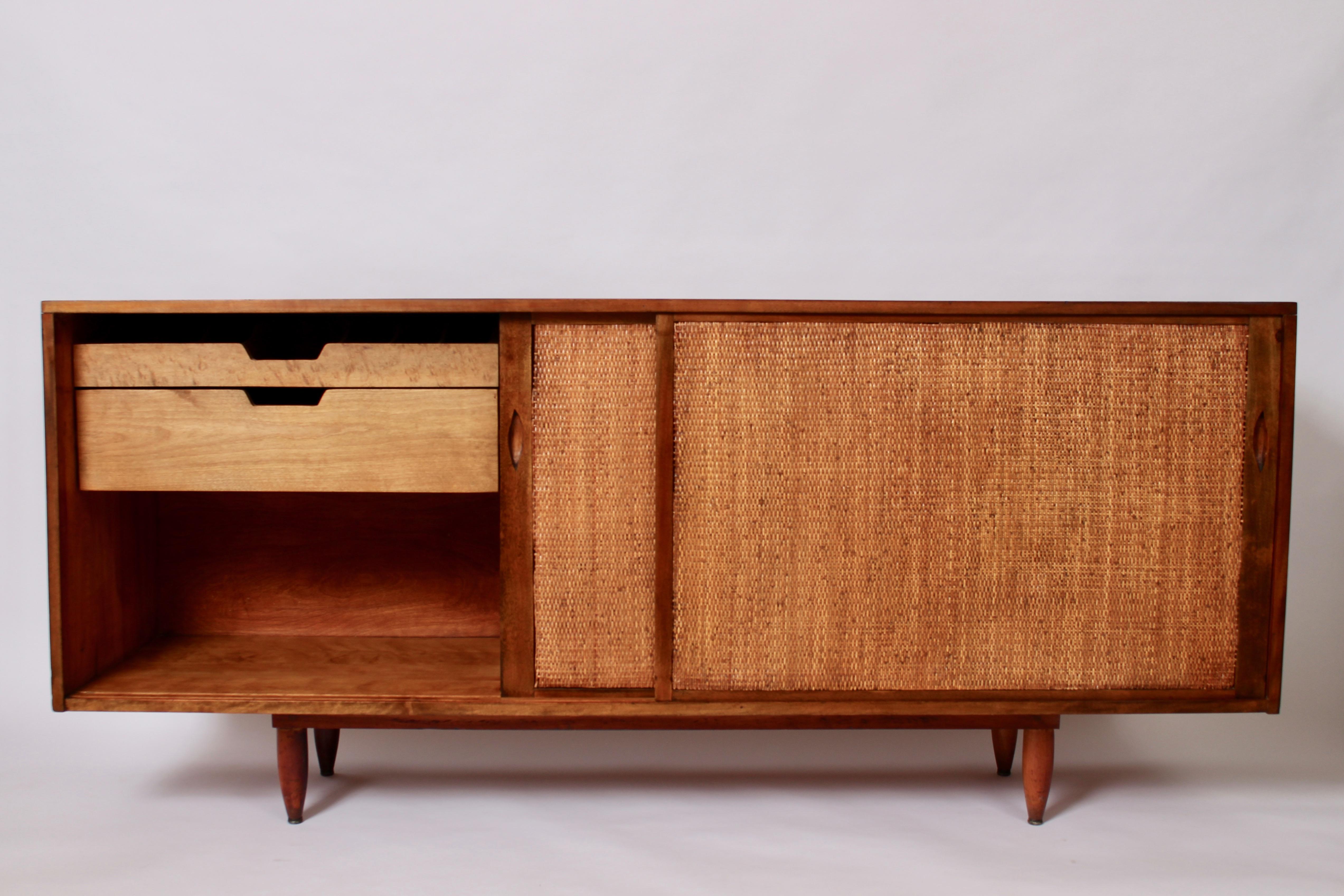 Substantial Six Foot Solid Walnut and Split Reed Credenza by Phillip Lloyd Powell, Early 1950's.  Featuring a rectangular Walnut frame and sliding Split Reed front. Dovetail cabinet construction, doweled legs, two 25W Bird's-Eye Maple left side
