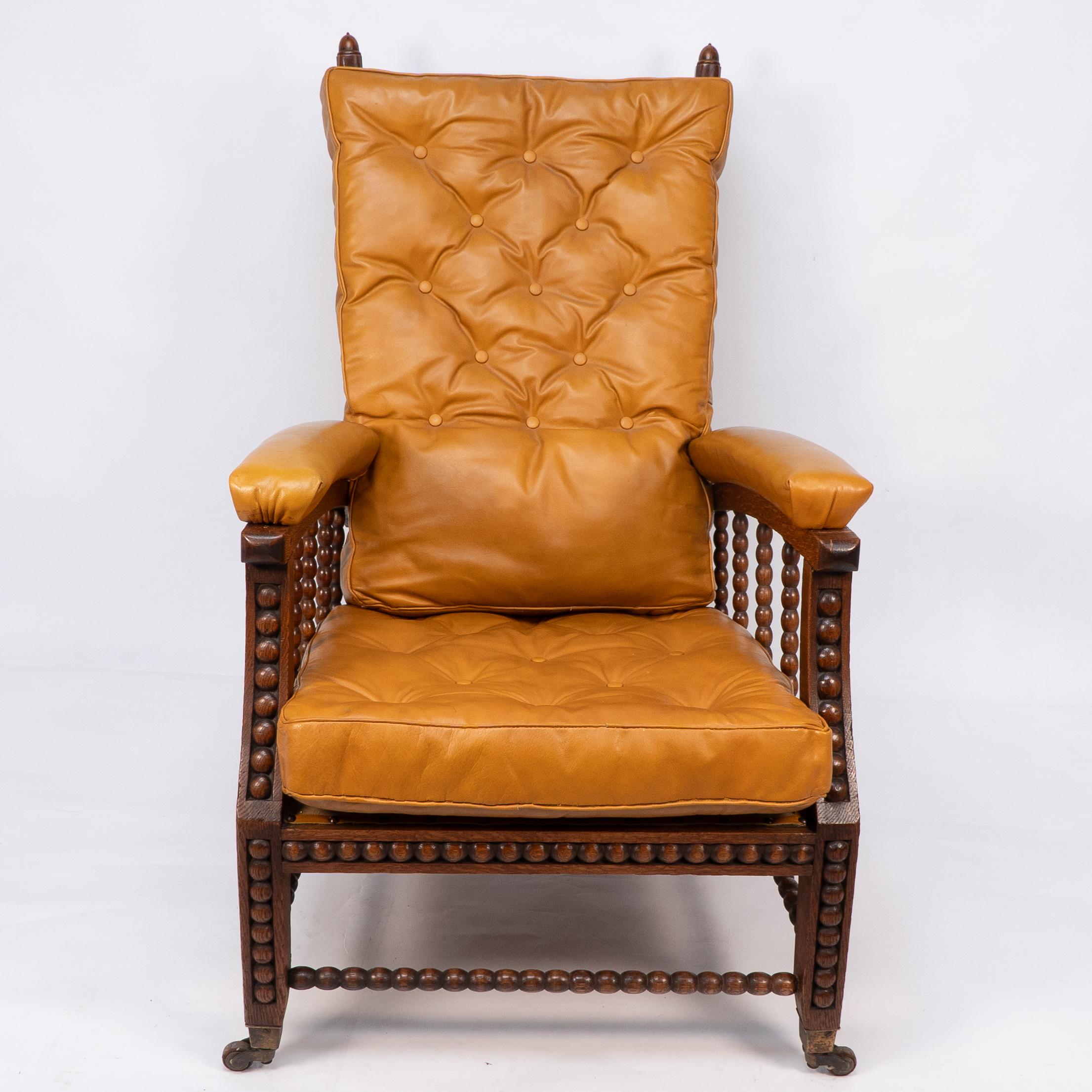 Phillip Webb for Morris and Co. Designed in C1866.
A rare Aesthetic movement oak adjustable reclining armchair with good quality tan leather button back upholstery. The arched arms with leather armrests united to the arched legs by bobbin turned
