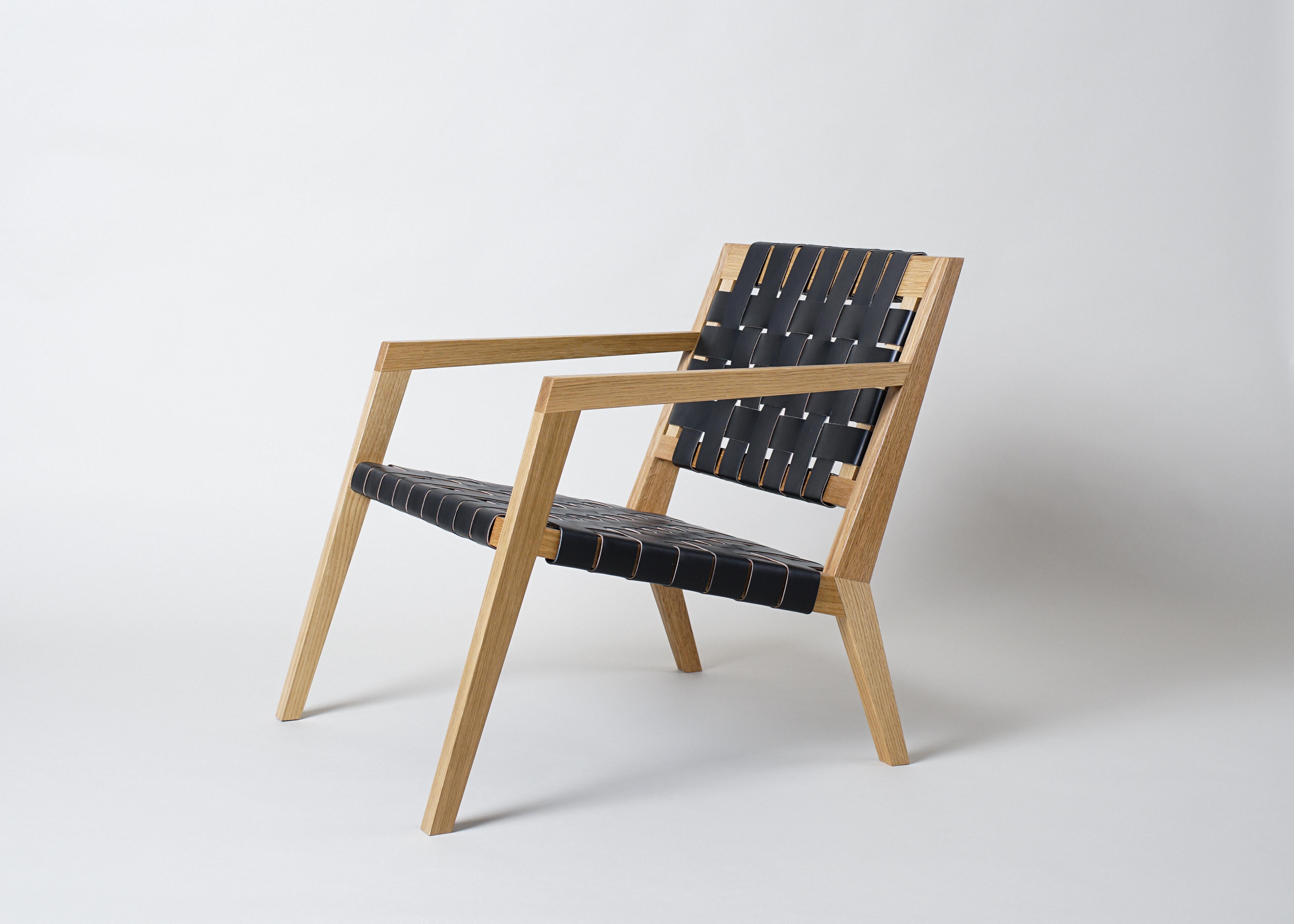 Le fauteuil de salon Nadine de Phloem Studio est un fauteuil de salon moderne et contemporain avec un cadre en bois massif et un siège en cuir tressé. Avec une menuiserie cannelée artisanale exposée et un gracieux dossier incurvé en bois massif