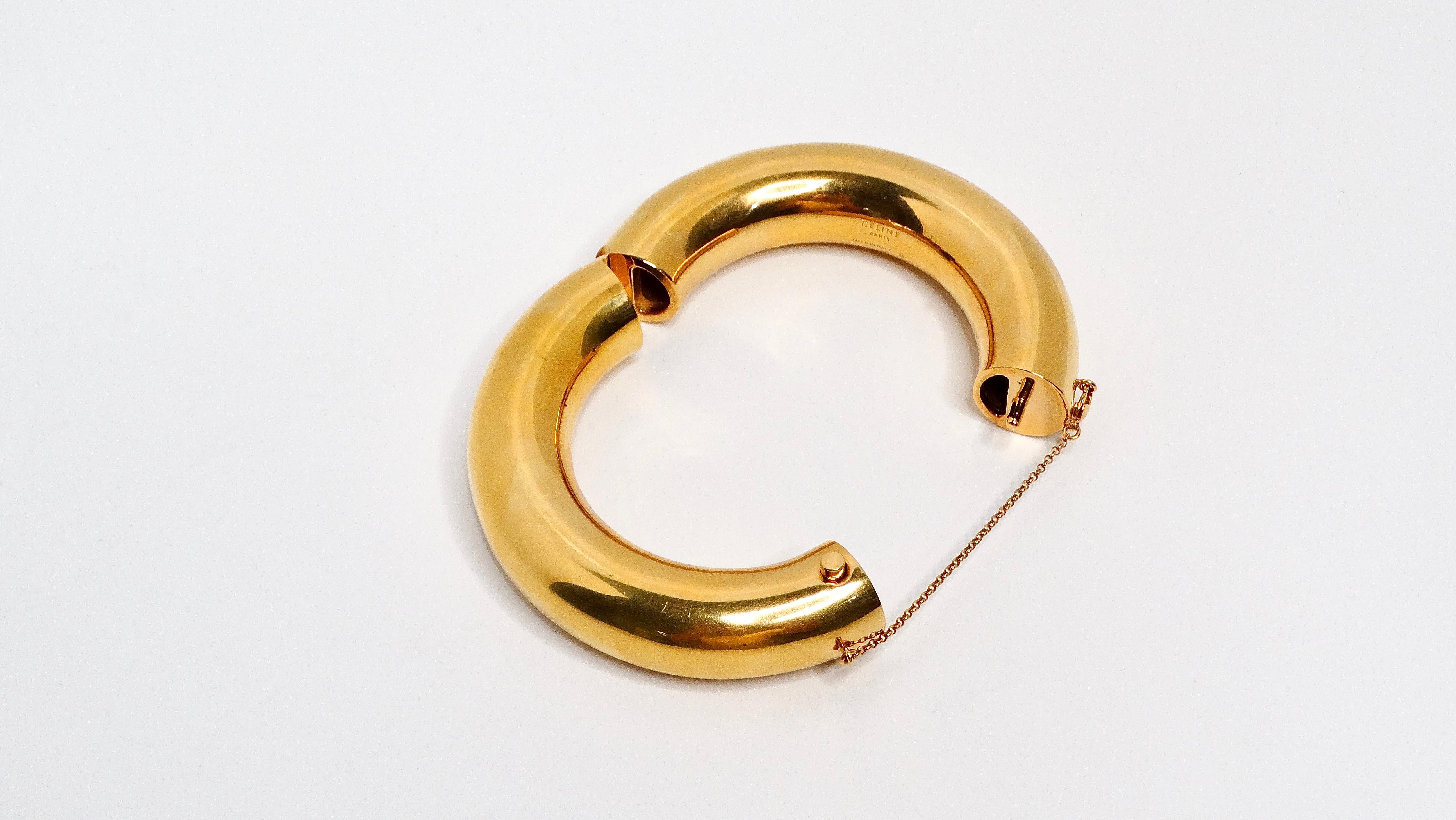 Phoebe Philo for Celine 24k Plated Gold & Brass Bangle is a stunning piece that embodies the designer's iconic minimalist aesthetic and attention to detail. This thick tubed bangle features a sleek and simple design, opening elegantly at 1.75