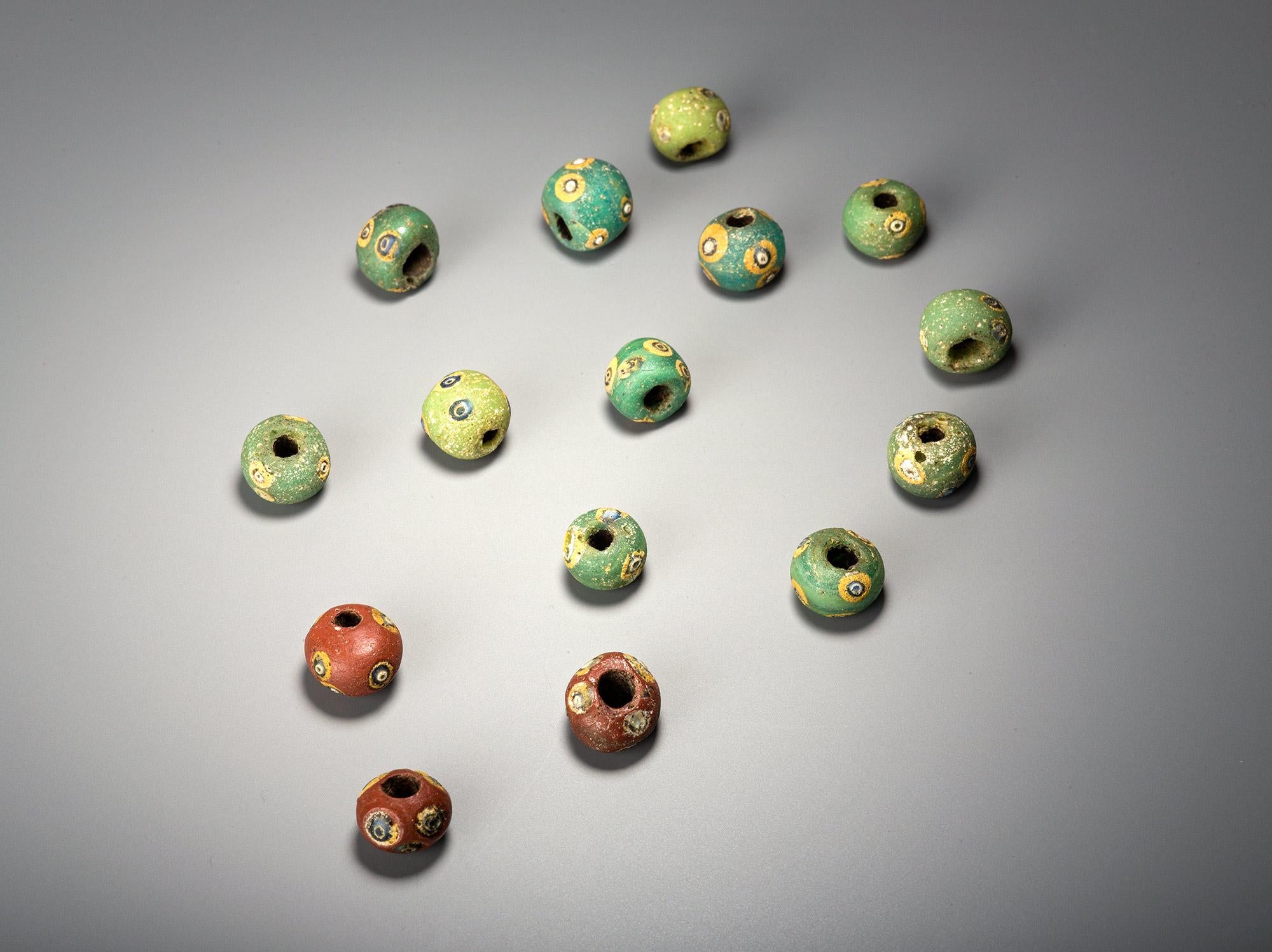 A fine set of 15 polychrome Phoenician glass eye beads.
The colours include red, green, yellow and blue.
One of the earliest examples of glassmaking, these ancient beads can be worn today by mounting on a necklace or a bracelet.
Accompanied by a