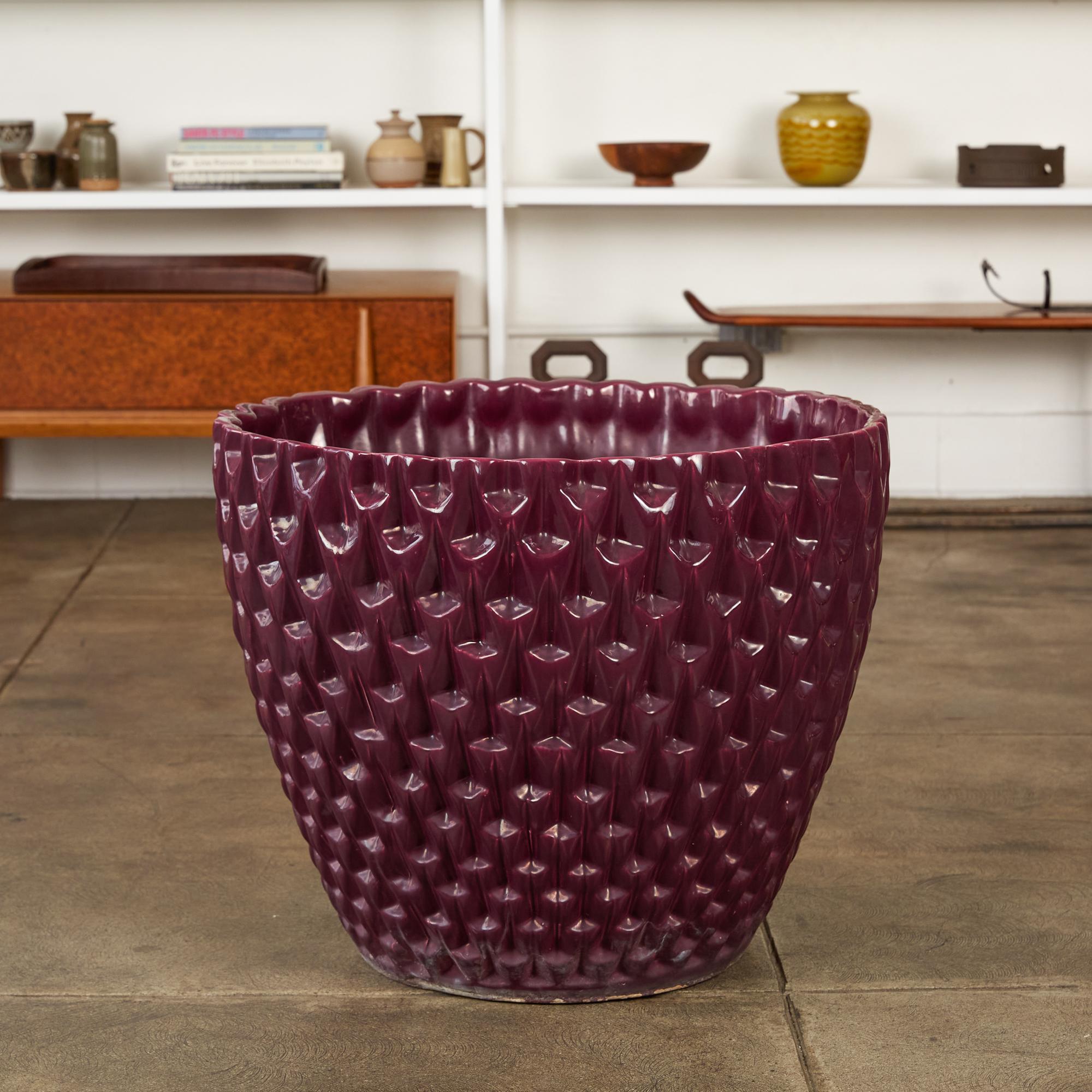 Designed by David Cressey in 1963 as part of the Pro/Artisan stoneware collection for Architectural Pottery, the slipcast Phoenix planter has a bowl shape with an allover geometric relief. This example is has an eggplant purple glaze with a glossy