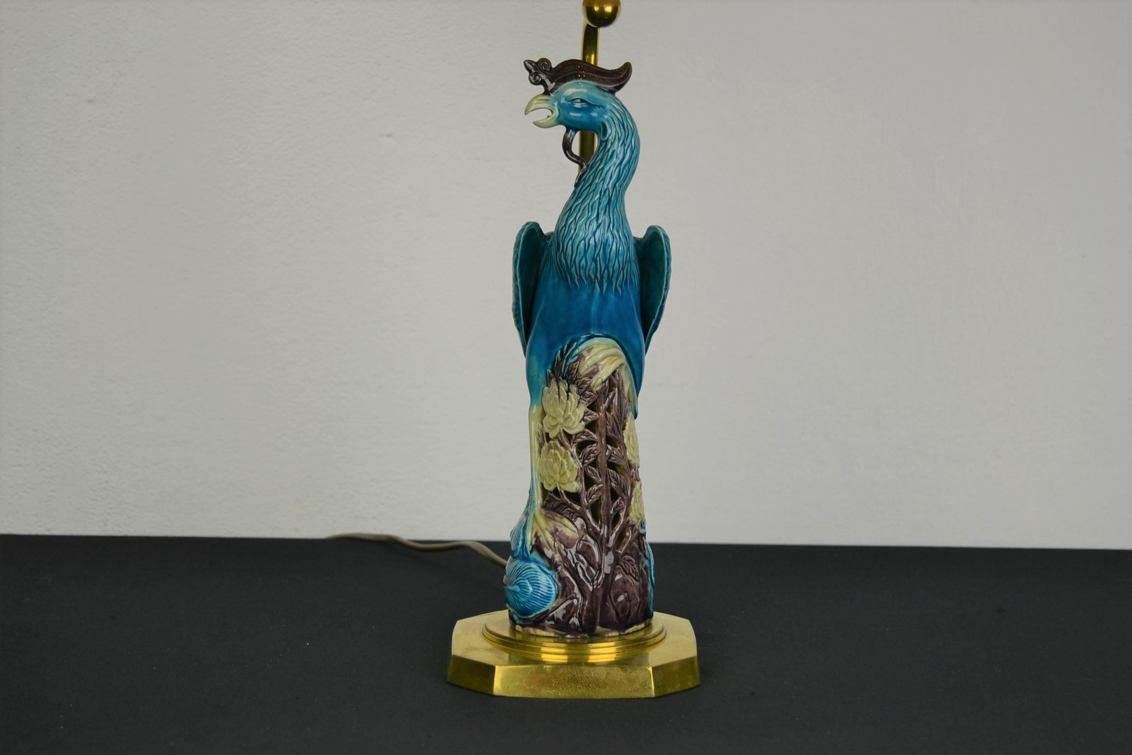 Great looking Phoenix Bird table lamp.
A blue turquoise very detailed ceramic Phoenix bird with lots of flowers under. 
Stands on a brass base. 

Comes with a vintage lampshade which fits the colors of the light well: 
a pink - purple lampshade