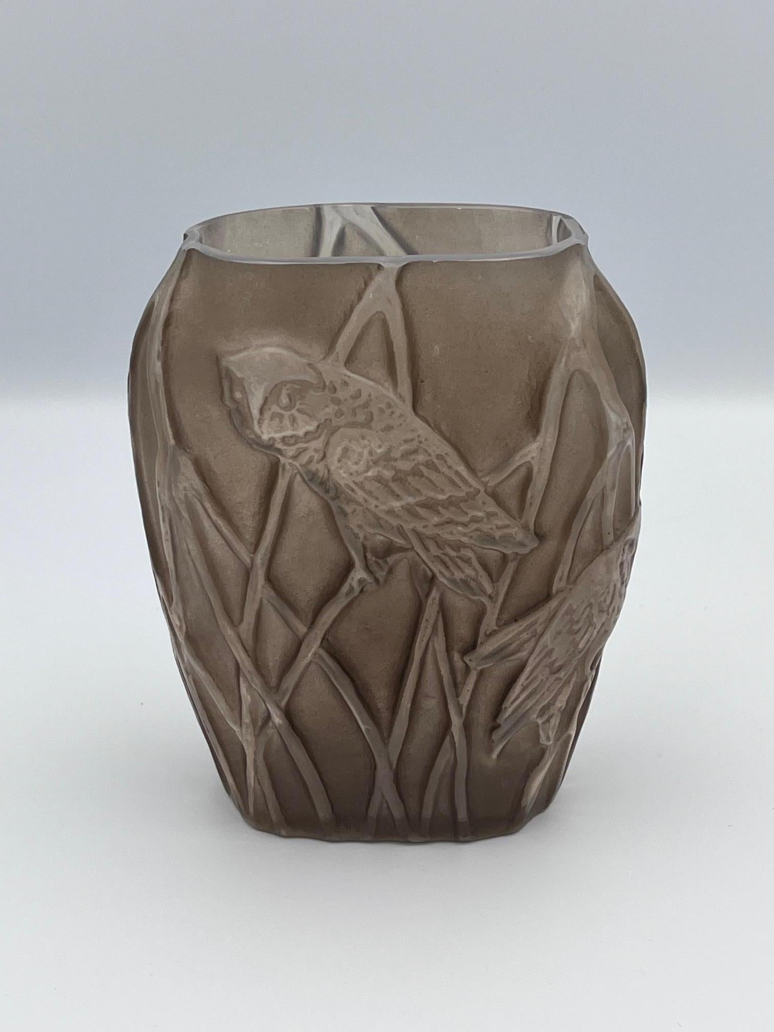 Il vaso Martele Screeching Owl di Phoenix Consolidated Glass del 1926 è un esempio straordinario di vetro artistico americano degli anni '20, con quattro gufi strillanti meticolosamente scolpiti appollaiati su canne che circondano il corpo. Il vaso