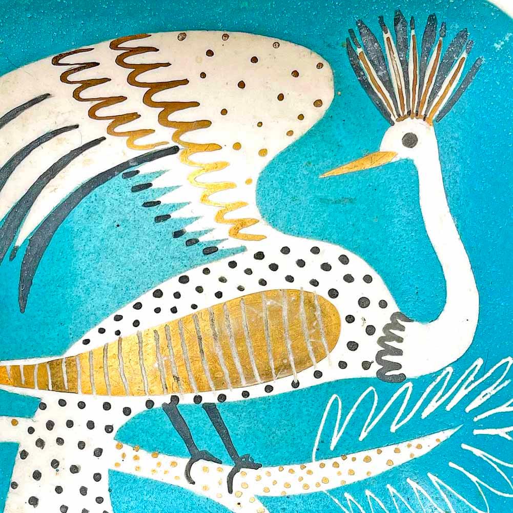 Die kühn gestaltete und glänzend glasierte Schale in Türkis-Aqua-, Schwarz-, Weiß- und Goldtönen zeigt einen exotischen Phönixvogel, der auf einem filigranen Ast ruht und einen Flügel in die Höhe streckt. Die Farben sind prächtig, vor allem das