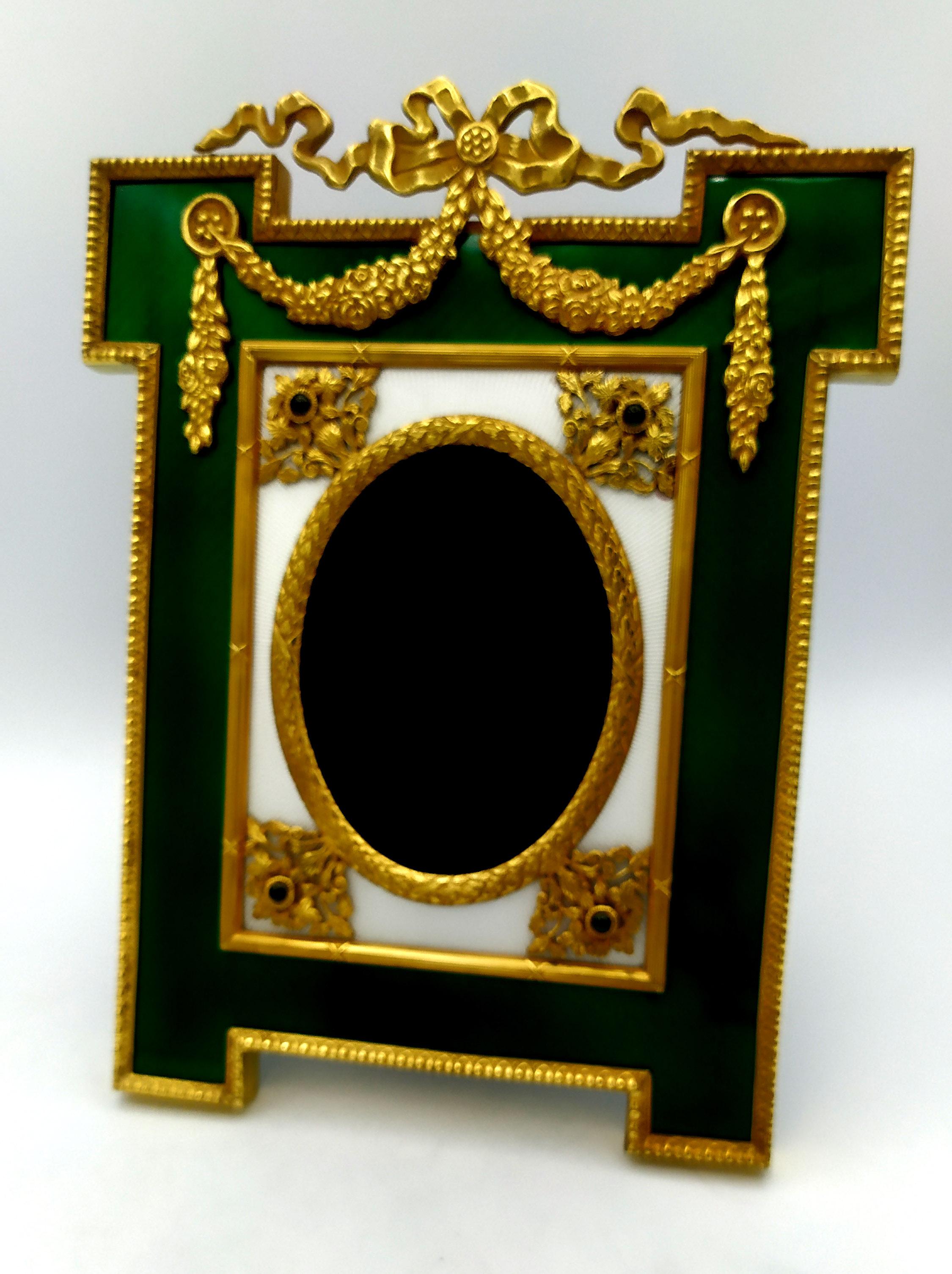 Large shaped frame for photographs in gold plated 925/1000 sterling silver with translucent two-tone fired enamels on guillochè and rich friezes in the French Empire Louis XVI style and with 4 round cabochon emeralds mm. 5. Velvet panel. External