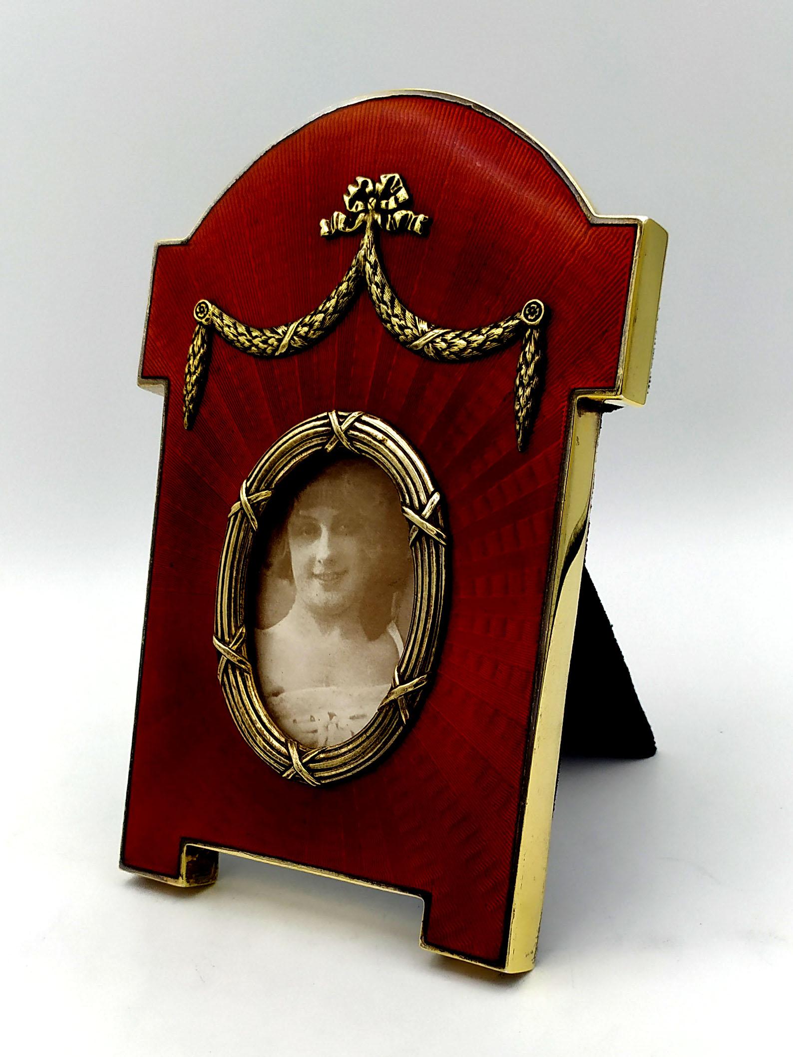 Shaped oval photo frame in 925/1000 sterling silver gold plated with translucent fired enamel on sunburst guillochè and Louis XVI French Empire style ornaments. External dimensions cm. 13.2 x 19., Internal oval cm. 4.7 x 6.7. Weight gr. 366.