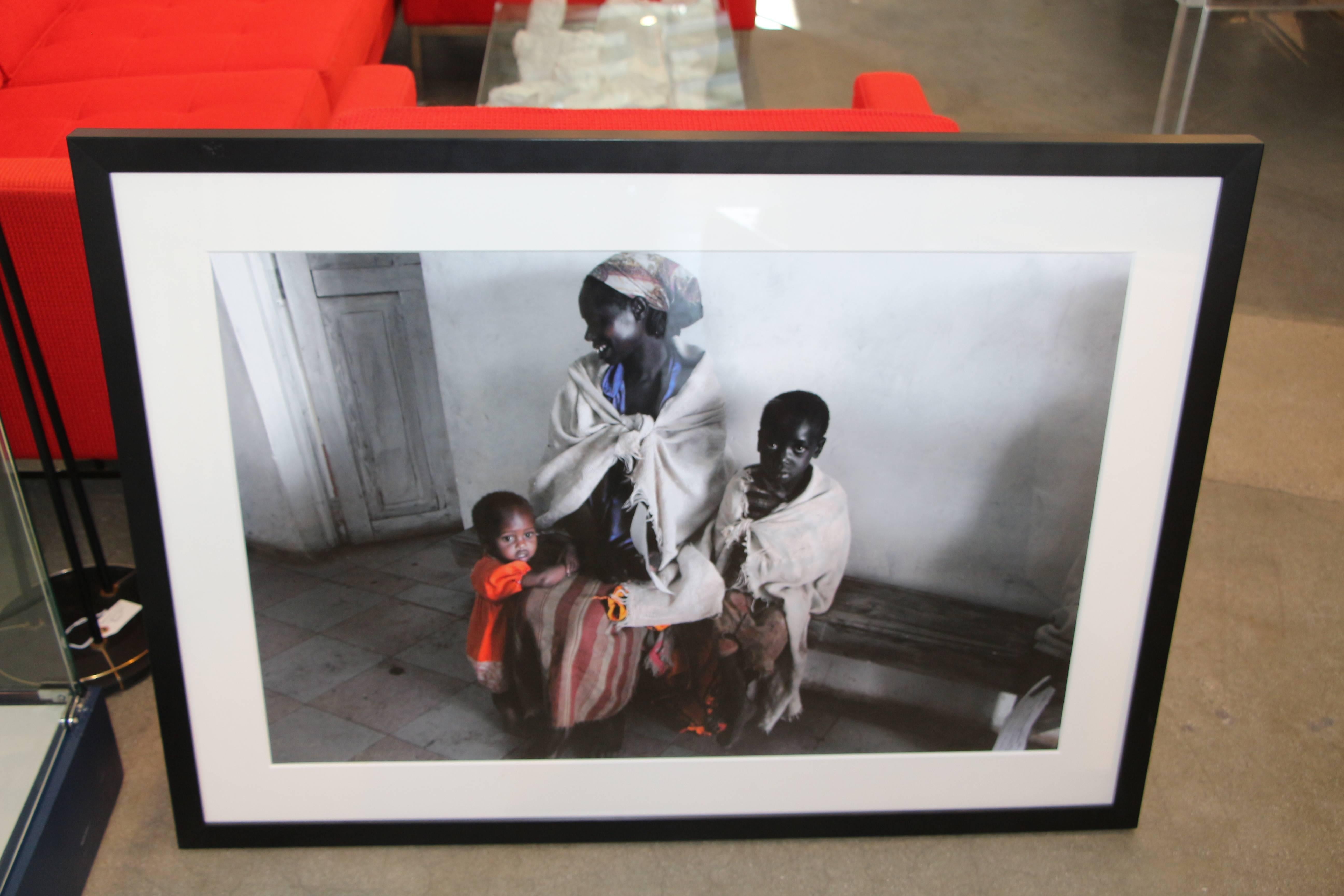 A striking photograph of a mother and children in Kenya by an unidentified artist.  Titled. dated and signed 2009 Kenya. Medium unidentified, possibly an archival inkjet print, nicely framed and matted. Image is slightly out of focus, whether that