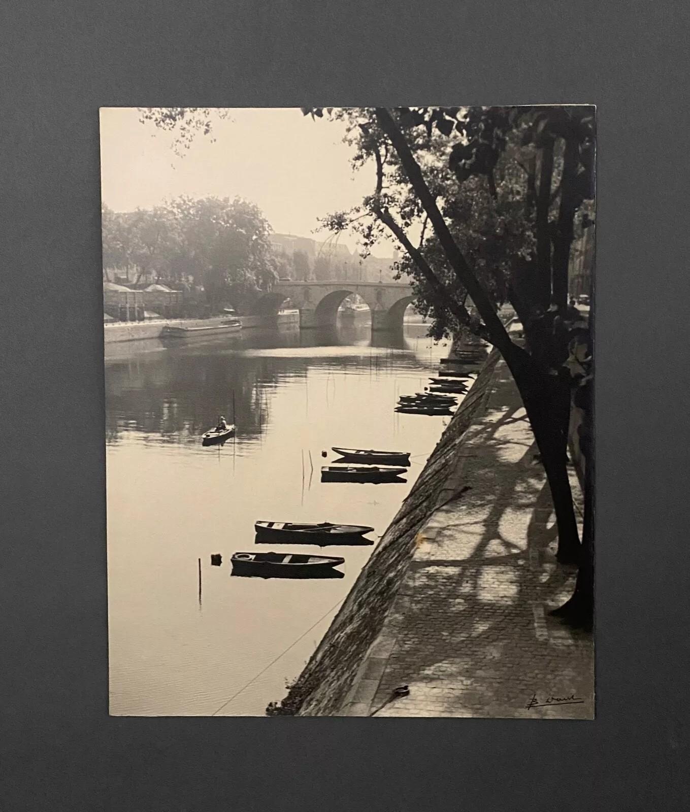 This original photograph by Bernard Darot is mounted on cardstock and signed in the lower right corner.

It depicts the Quai des Grands-Augustins, a historic quay along the left bank of the Seine in Paris’s 6th arrondissement, between Pont