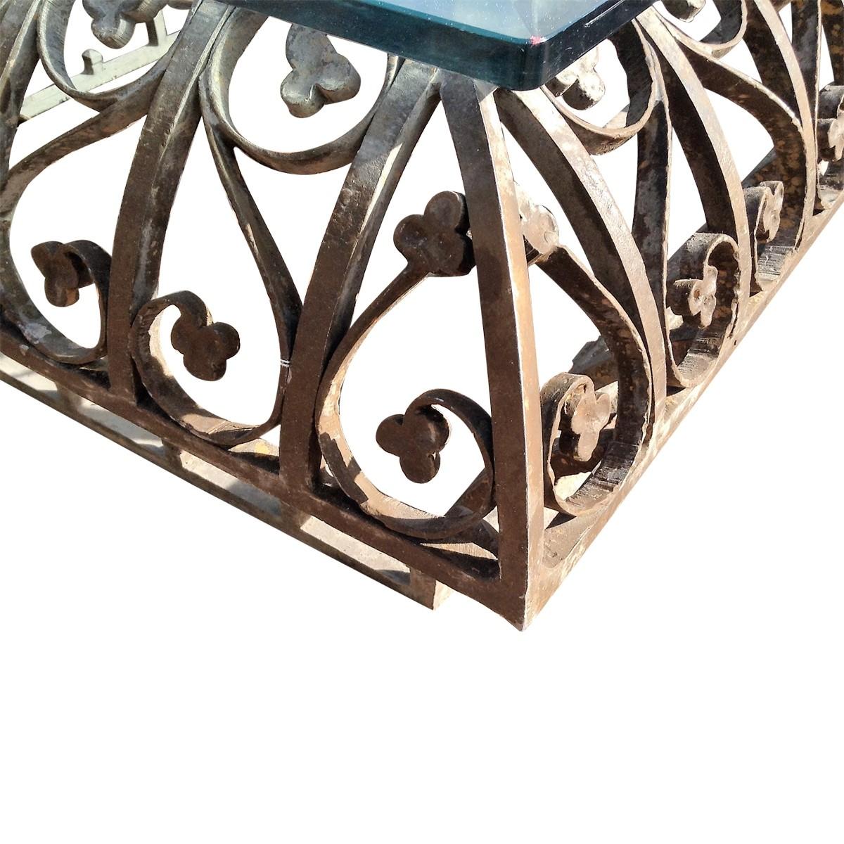 Phyllis Morris is renowned for crafting furniture with dramatic style from luxurious materials. Bold but sleek, this eye-catching coffee table features a patinated wrought iron base with a foliate and scroll motif. A rectangular shaped smoky glass