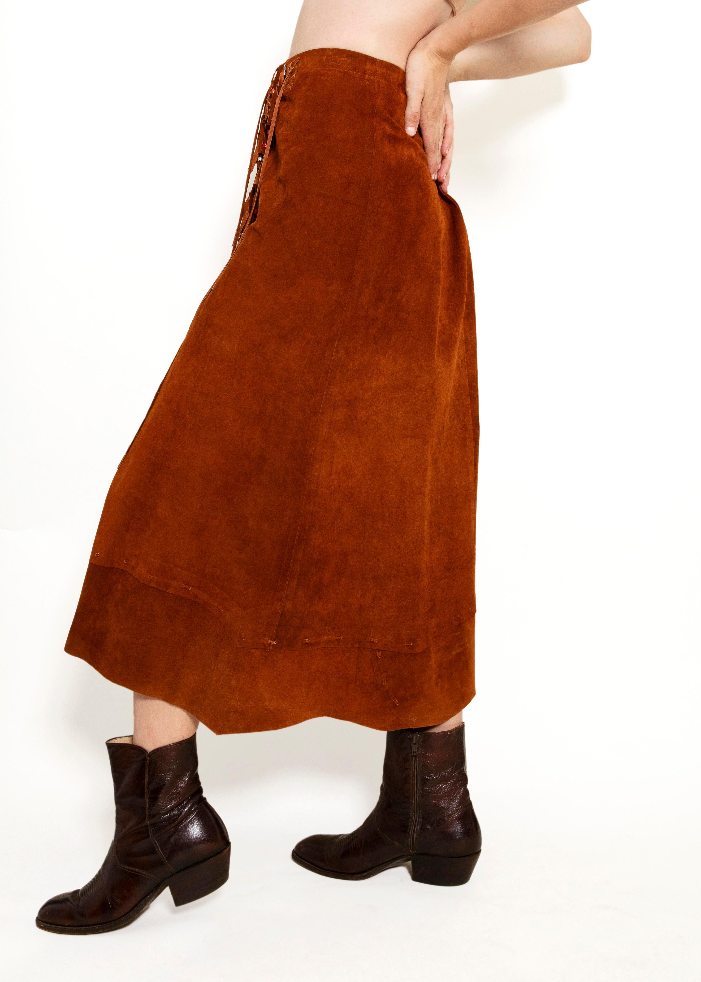 Unleash your inner boho goddess with the Pia Rucci Leather Fringe Skirt. Crafted from burnt sienna suede fabric, this skirt features tassels adorned with multicolor beads, adding a playful touch to its asymmetric design. Go ahead, sway and spin to