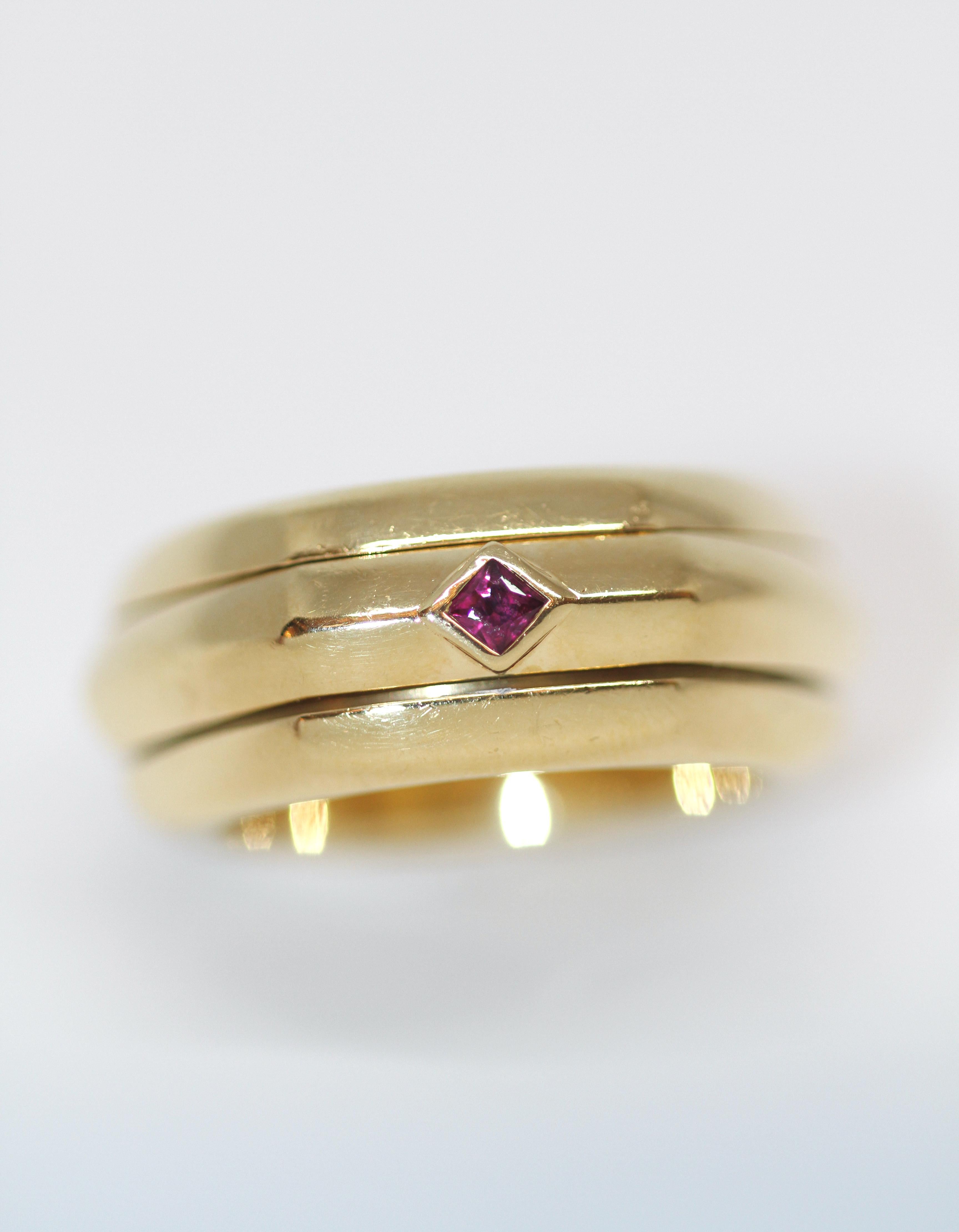 This elegant ring signed from the house of Piaget is made in 18kt yellow gold and set with a ruby. 
The hexagonal center ring is turning in between the other 2 bands.

Year: 1998
Collection: Possession
Material: 18 kt yellow gold and ruby
Size: