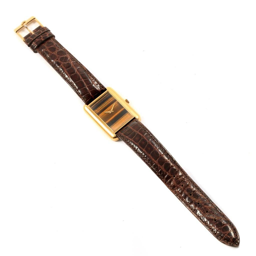 Piaget 18K Yellow Gold Tiger Eye Brown Strap Ladies Watch 9228. Manual-winding movement. 18K yellow gold rectangular case 23 x 34 mm. 18K yellow gold fixed bezel. Mineral glass crystal. Tiger eye dial with 18K yellow gold Dauphine hands. Custom