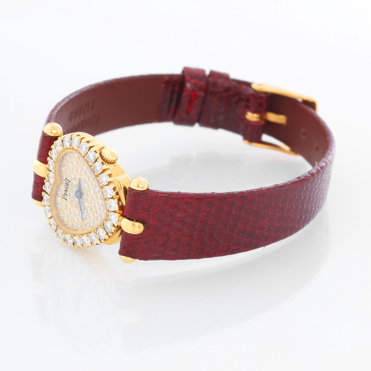 Piaget 18K Yellow Gold Heart Shaped Watch - Quartz. 18K Yellow gold with diamond bezel; 24 Factory Set Diamonds ( 20 mm ). Pave diamond dial; 93 Factory Set Pavé-Set Diamond Dial. Burgundy leather  strap with gold color buckle. Pre-owned with Piaget