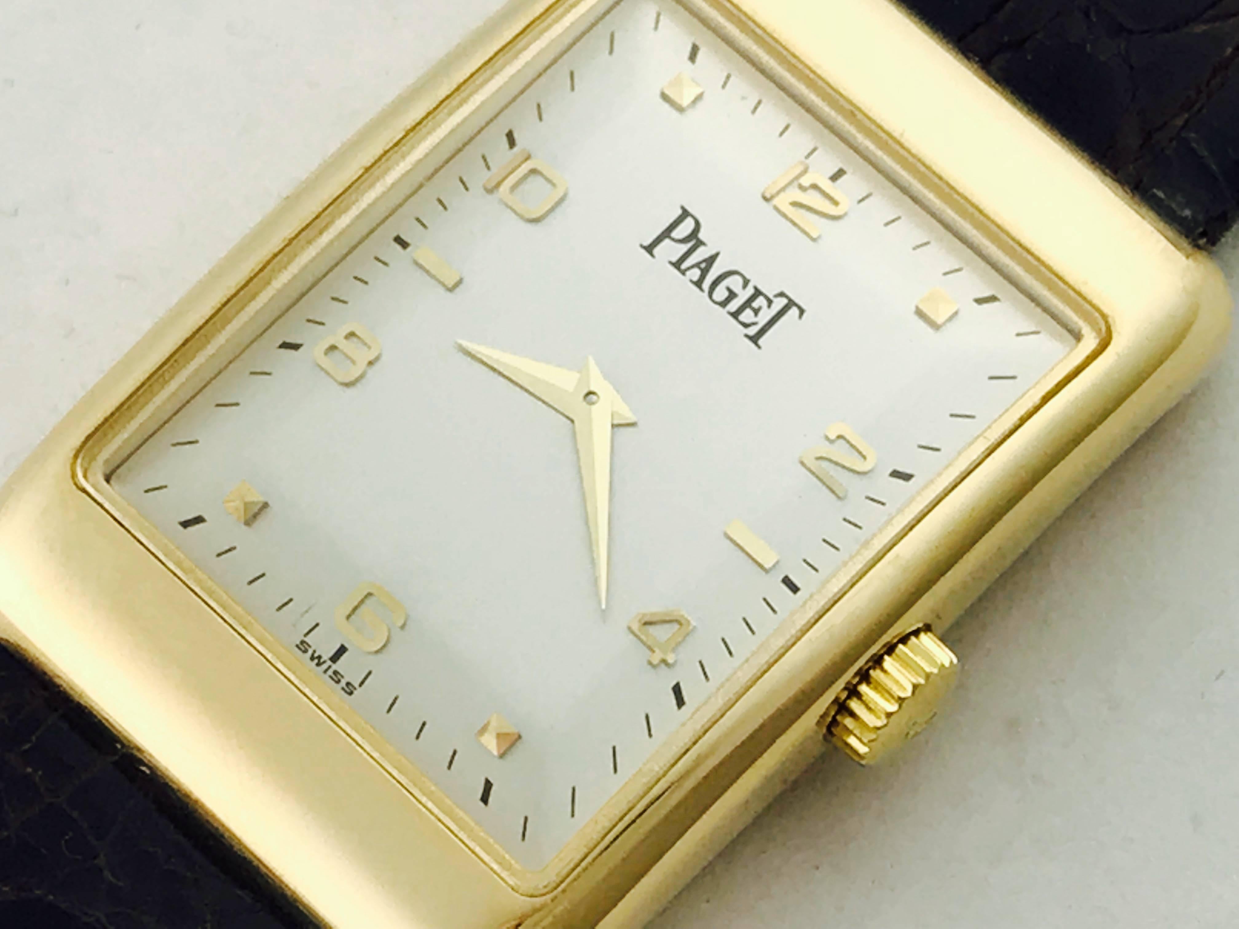 Piaget Mens 18k yellow gold manual wind strap wrist watch. 18k Yellow Gold rectangular style case (24x35mm), Dark brown alligator strap with 18k yellow gold Piaget buckle,  Silvered Dial with yellow gold hour markers and Arabic numerals. Certified