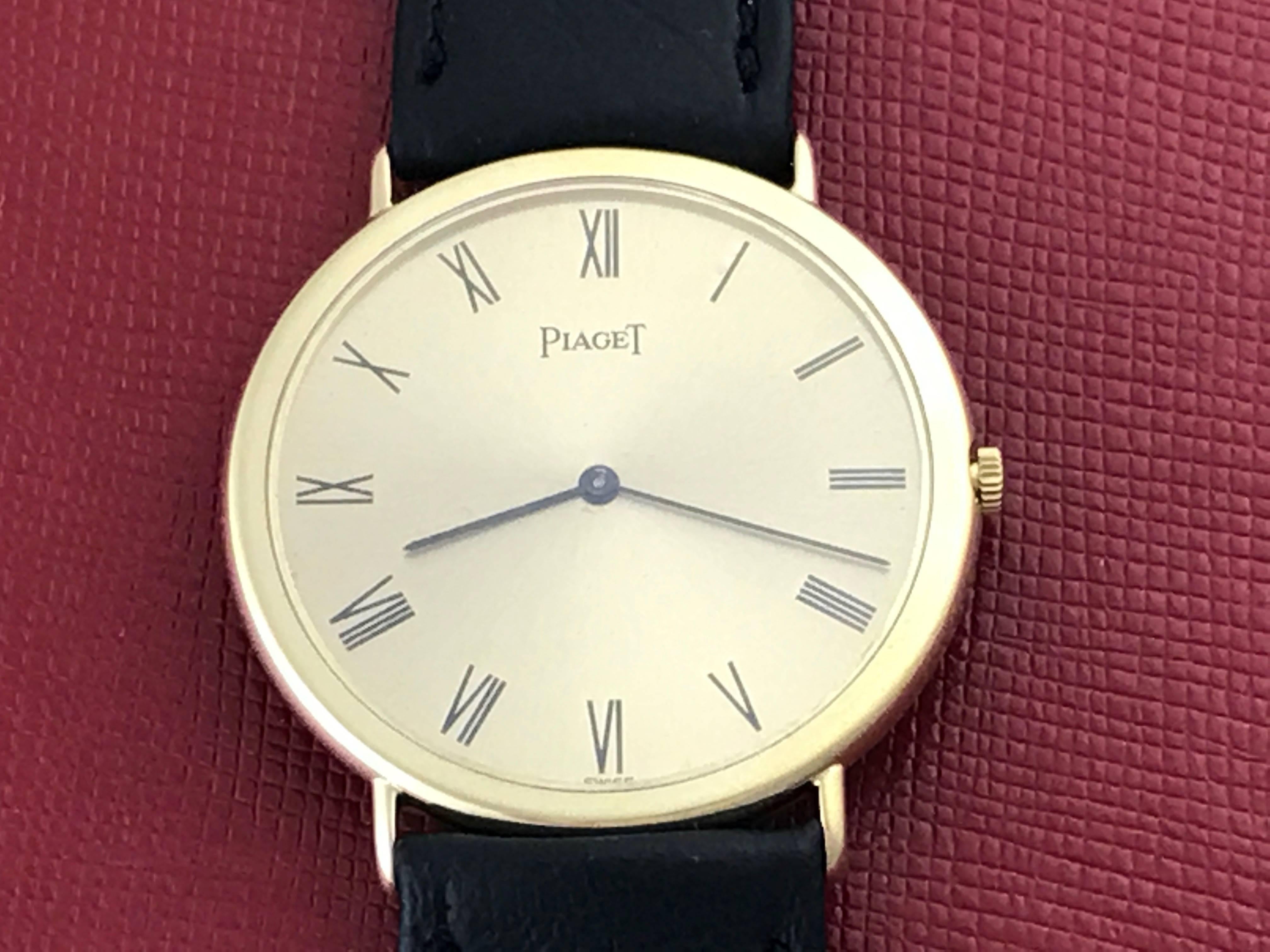 Piaget Pre Owned Mens Manual Winding wrist watch. Champagne Dial with black Roman numerals 18k Yellow Gold round style case (32mm), black strap with yellow gold filled buckle. Classic, simple, beautiful! Ready to ship! Inventory # C44390