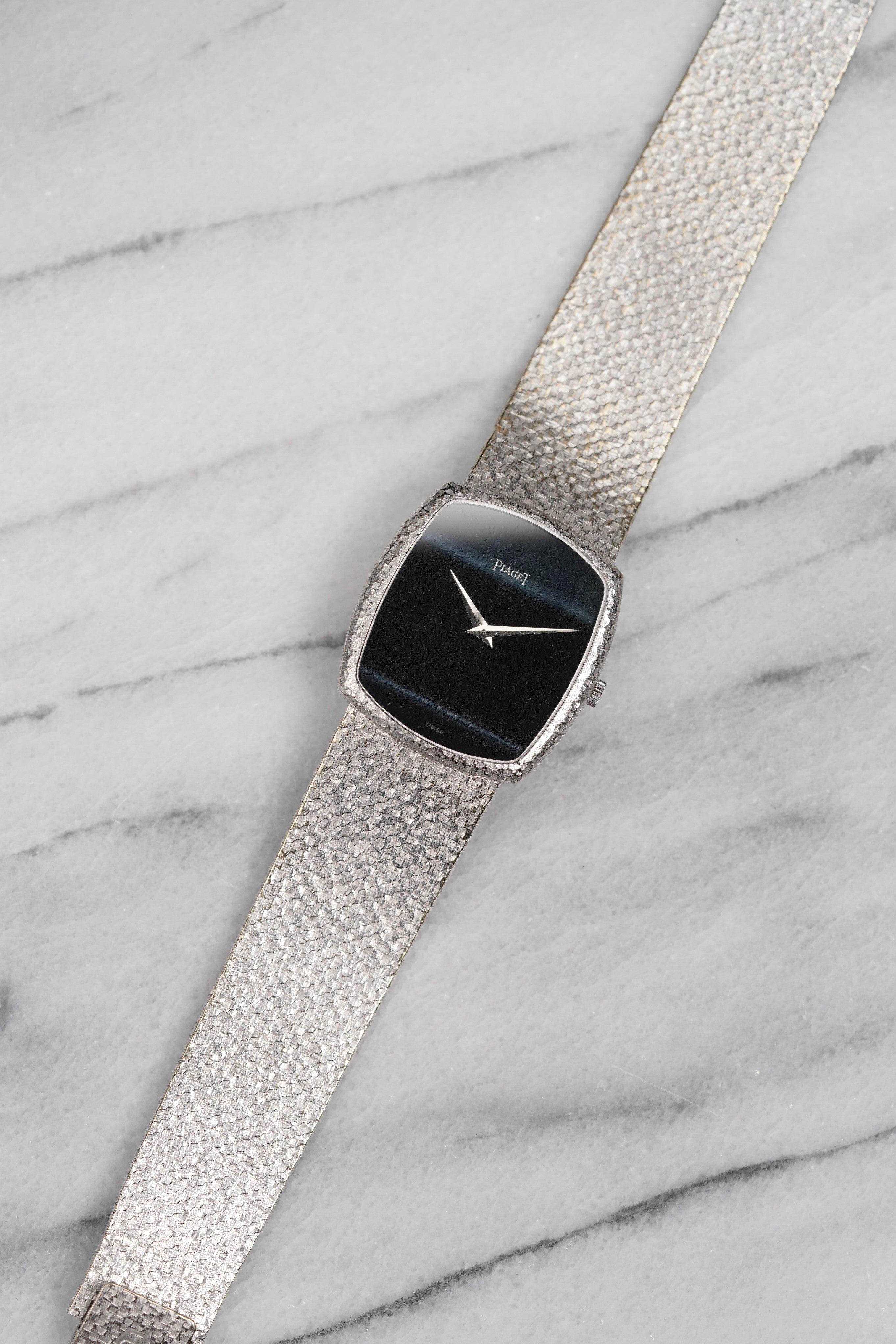 Voici une Piaget référence 9741 à remontage manuel en or blanc 18 carats avec un rare cadran noir et bleu en pierre œil de faucon datant des années 1980. Les mesures comprennent un boîtier tonneau de 28 mm de diamètre et le bracelet s'adapte à un