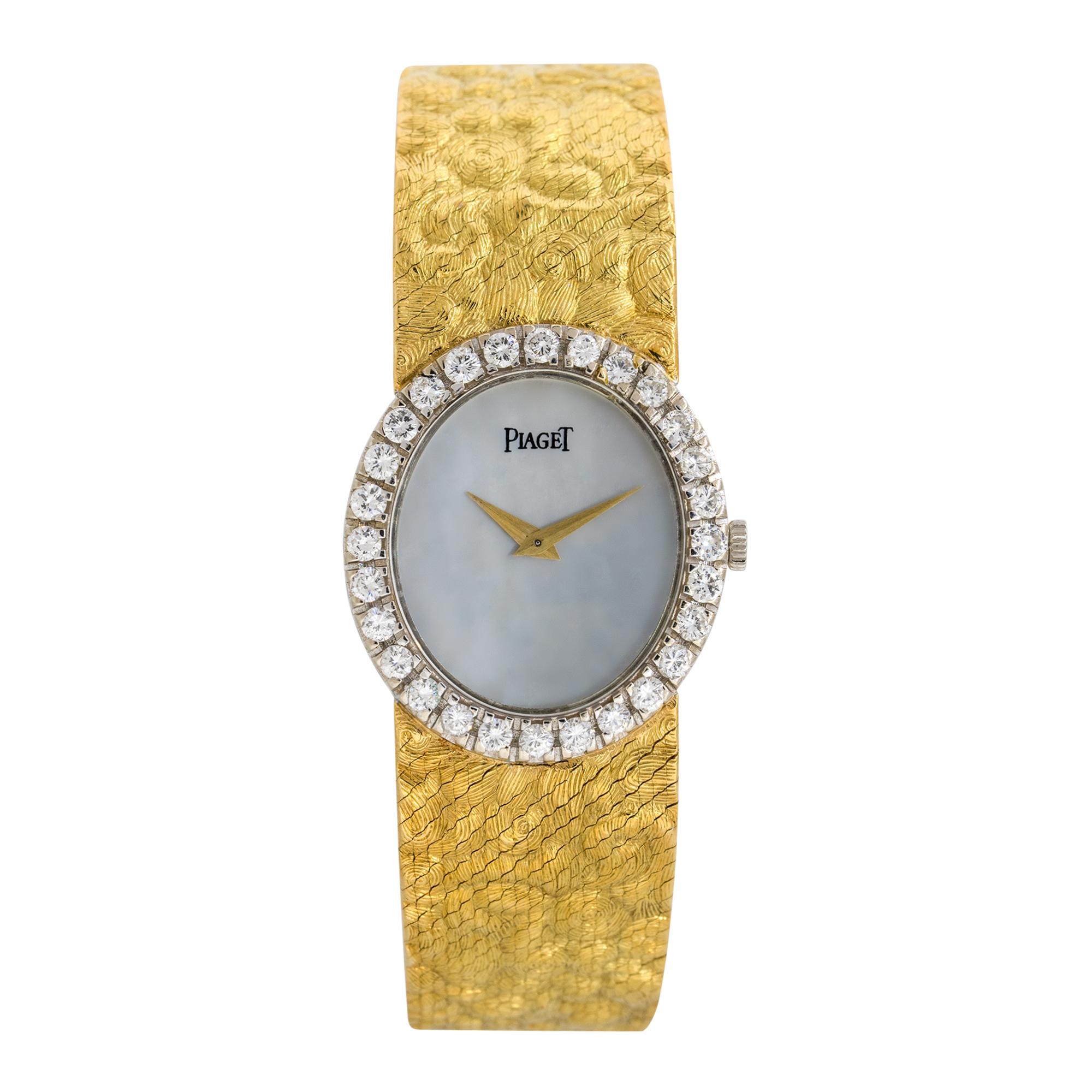 Brand: Piaget
Model: 9814
Case Material: 18k Yellow Gold
Bezel: Round Diamond bezel
Dial: White Mother of Pearl dial with yellow gold hands
Bracelet: 18k yellow gold two piece bracelet
Crystal: Sapphire Crystal
Size: Will fit up to a 6.5