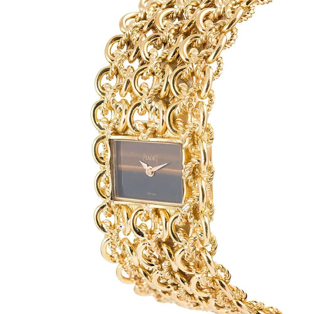 Sophisticated and glamourous, this mid-century treasure nestles a rectangular tiger’s eye watch in a woven bracelet of high-polished and matte-finished golden threads. The bracelet is of Piaget manufacture and measures 6.5 by 1 inch. It is finished
