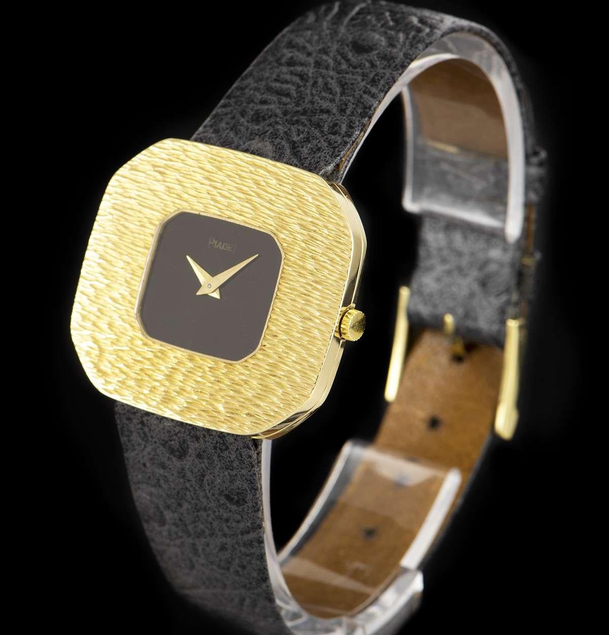 A 32 mm 18k Yellow Gold Vintage Men's Dress Wristwatch, black dial with roman numerals, a fixed 18k yellow gold textured bezel, a brand new black leather strap (not by Piaget)with an original 18k yellow gold pin buckle, plastic glass, manual wind