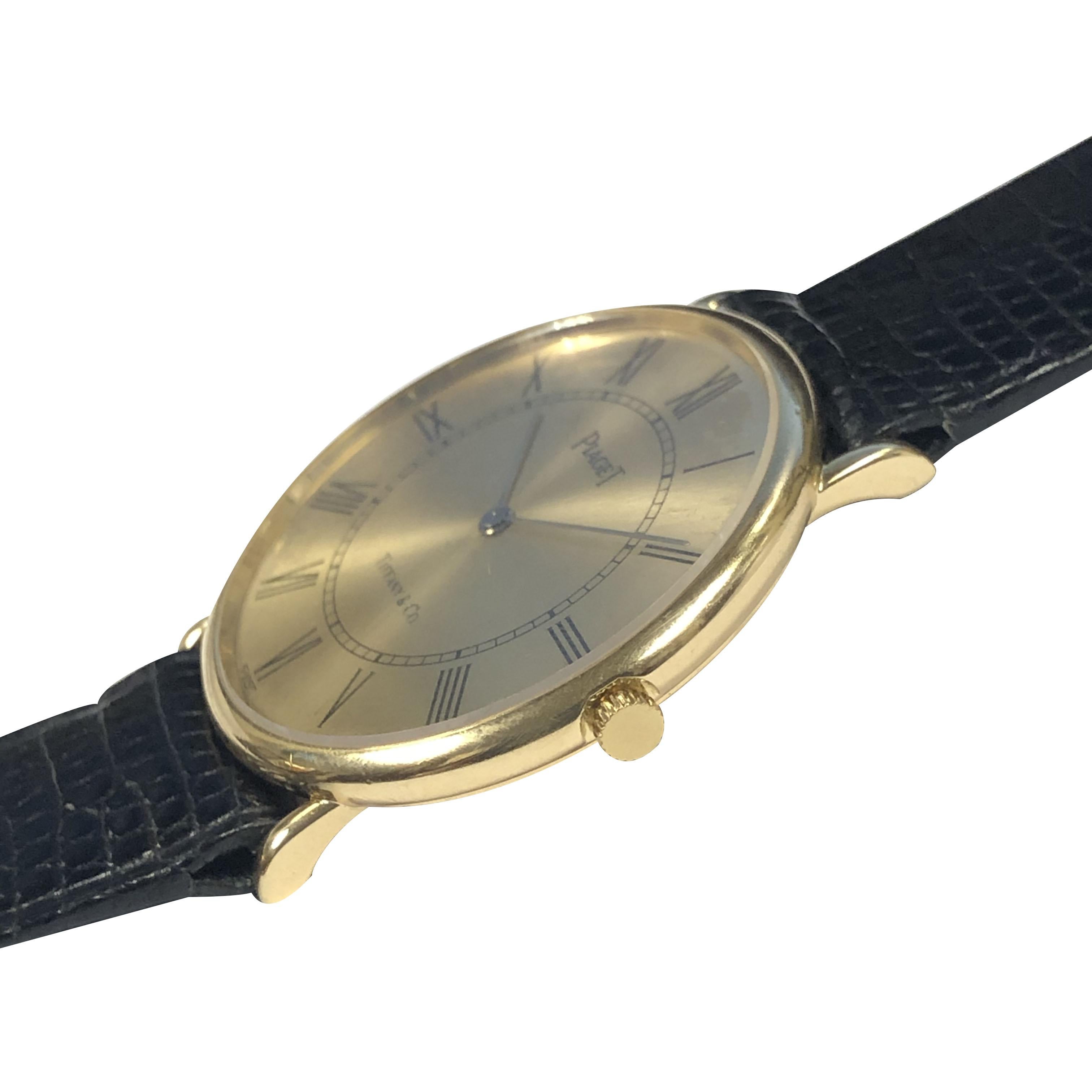Circa 1980s Piaget Retailed by Tiffany & Company.   30 M&M. Diamètre X 4 M.M. boîtier 2 pièces en or jaune 18 carats, mouvement mécanique 17 rubis à remontage manuel, cadran or avec chiffres romains noirs.  Chiffres. Nouveau bracelet Piaget en