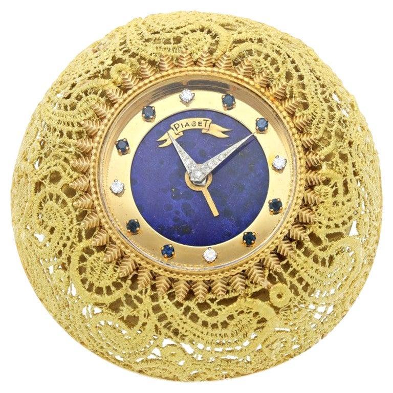 Piaget gold desk clock

Circa 1970

 24K Yellow Gold lace motif with lapis lazuli diamond & sapphire- set dial.

Dial: lapis lazuli, diamond and sapphire-set indexes, diamond-set hands

Caliber: circular mechanical 
Case: 24k yellow gold