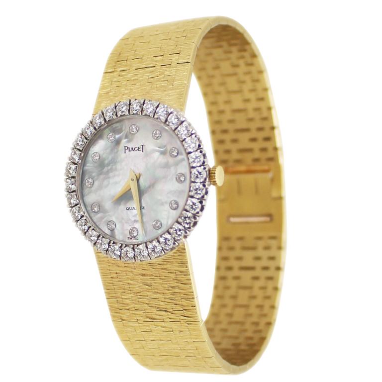 Circa 1980 Piaget ladies Wrist watch,  26 MM 18K yellow Gold 2 Piece case with a White Gold factory Diamond Bezel of Round Brilliant cuts Grading as F - G in color, VS in Clarity and totaling 1 carat. Quartz Movement, Gray - White Mother of Pearl