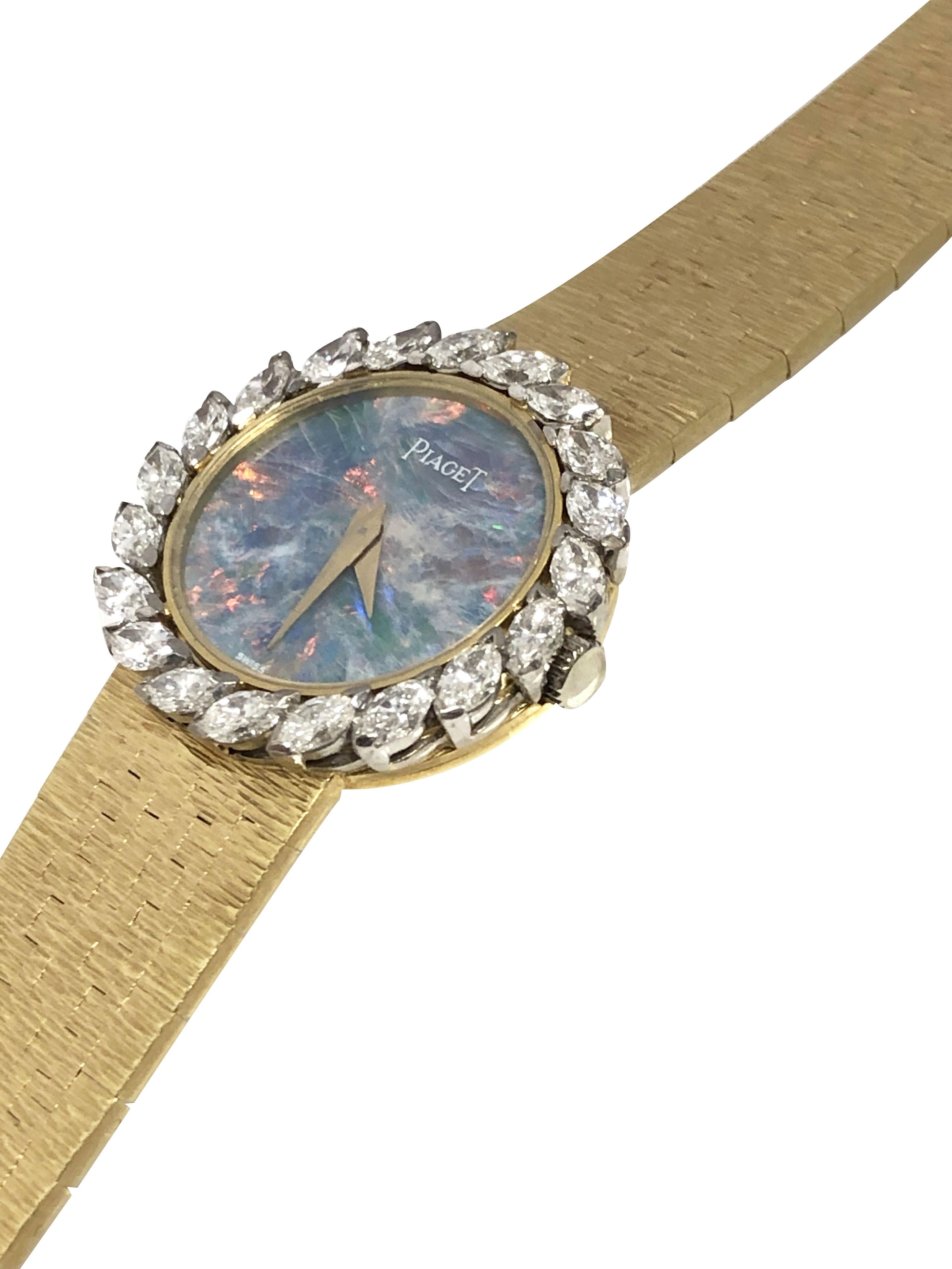 Circa 1980 Piaget Ladies Wrist Watch, 18K Yellow Gold 24 M.M. 2 piece case, bezel set with Marquise shape Diamonds totaling 1.50 Carats and Grading as G in color and VS in clarity. Firey Opal dial with bold colors of Blue, Red and Green. 17 Jewel