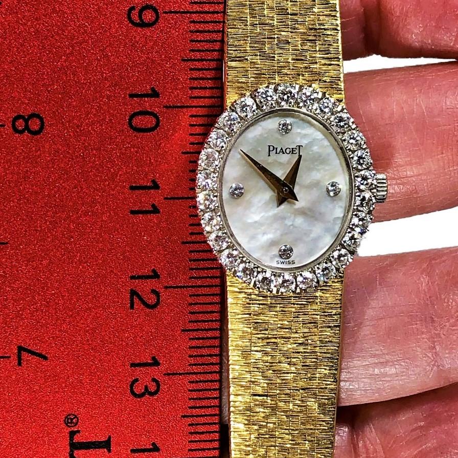 This elegant, petite size, ladies 18K yellow gold Piaget watch has a vertical oval 
shaped Mother-of-Pearl dial with four diamond markers, surrounded by a diamond
bezel set with sixteen brilliant cut diamonds.. The total approximate diamond